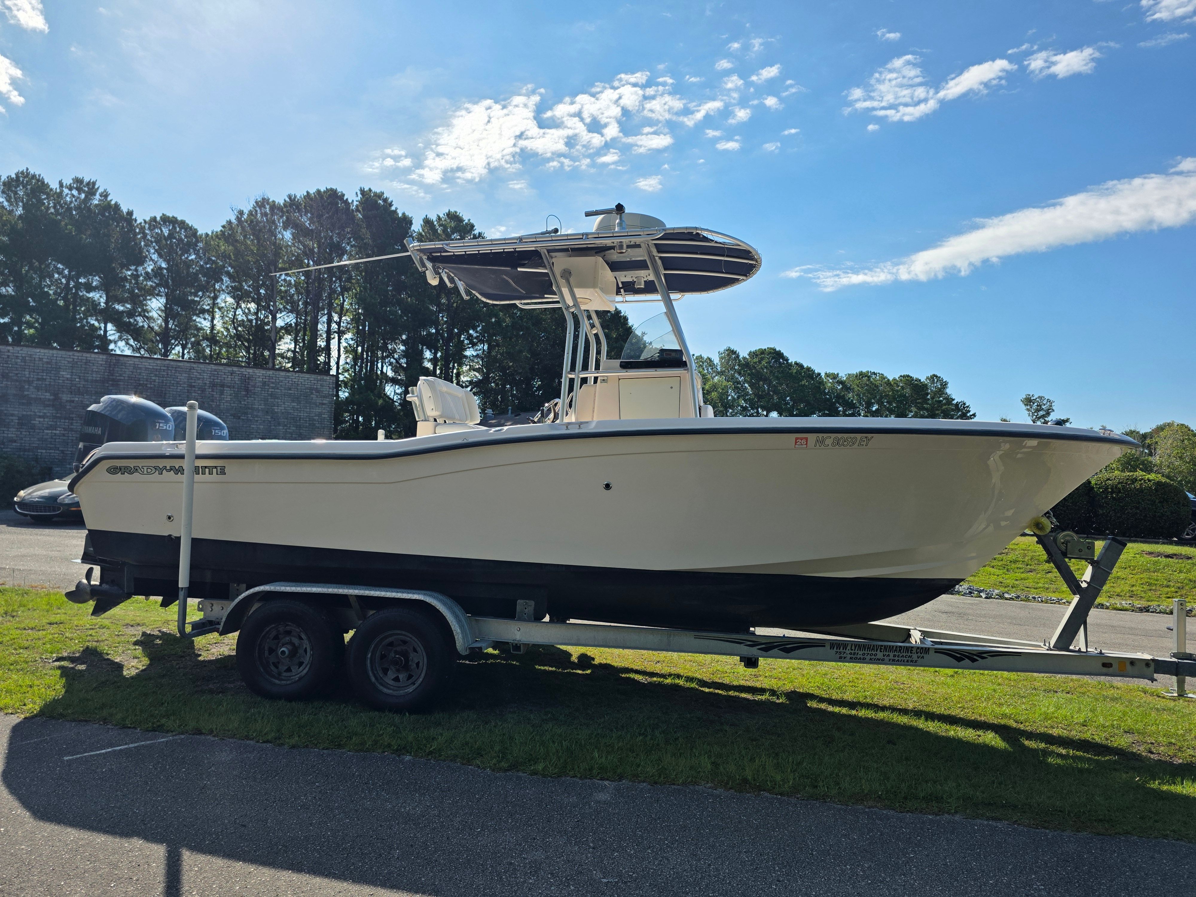 A 2006 Grady-White 257 boat on a trailer, surrounded by trees and blue sky.