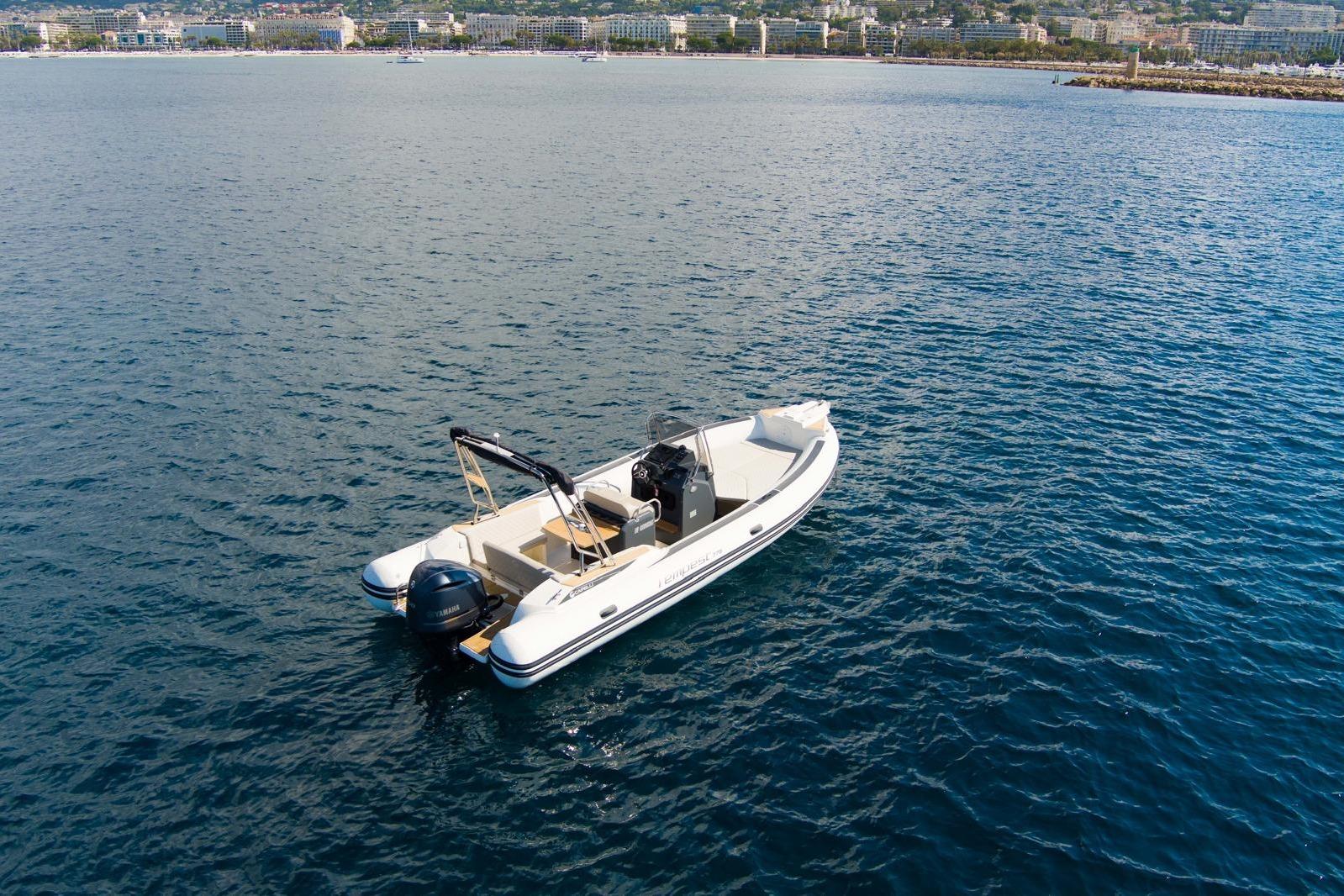 2020 Capelli Tempest 775 boat on calm blue water near a coastal city.