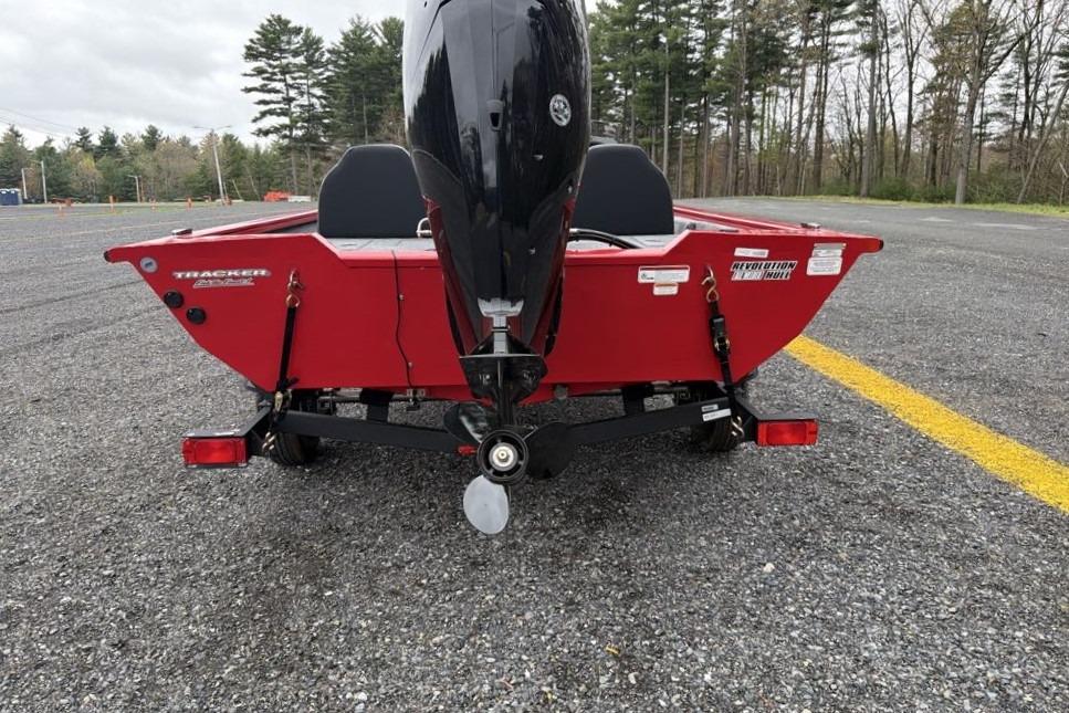 2026 Tracker Pro Team 175 boat, red exterior, parked on gravel with trees in background.