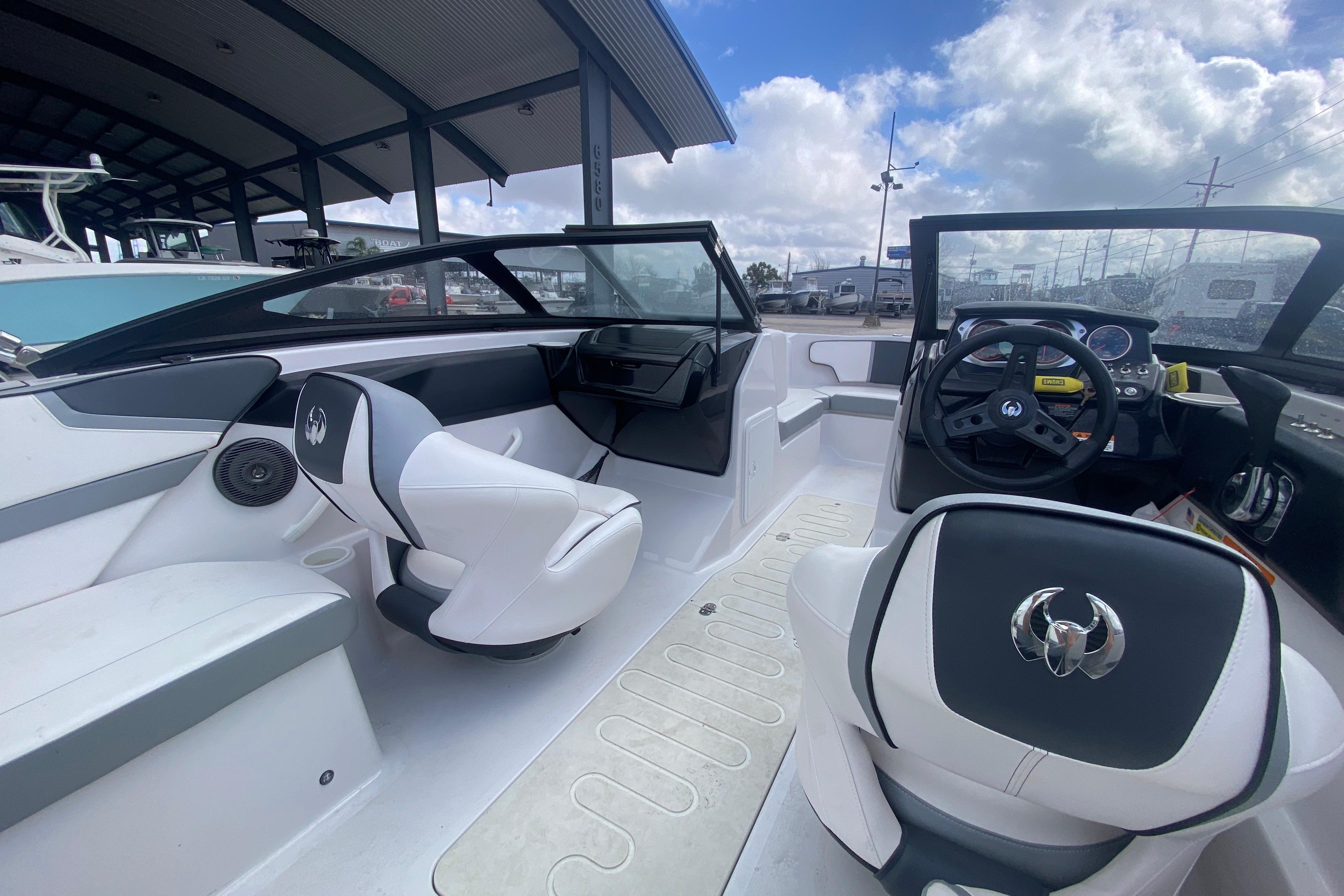 2018 Scarab 215 G boat interior with modern seating and steering wheel under a cloudy sky.