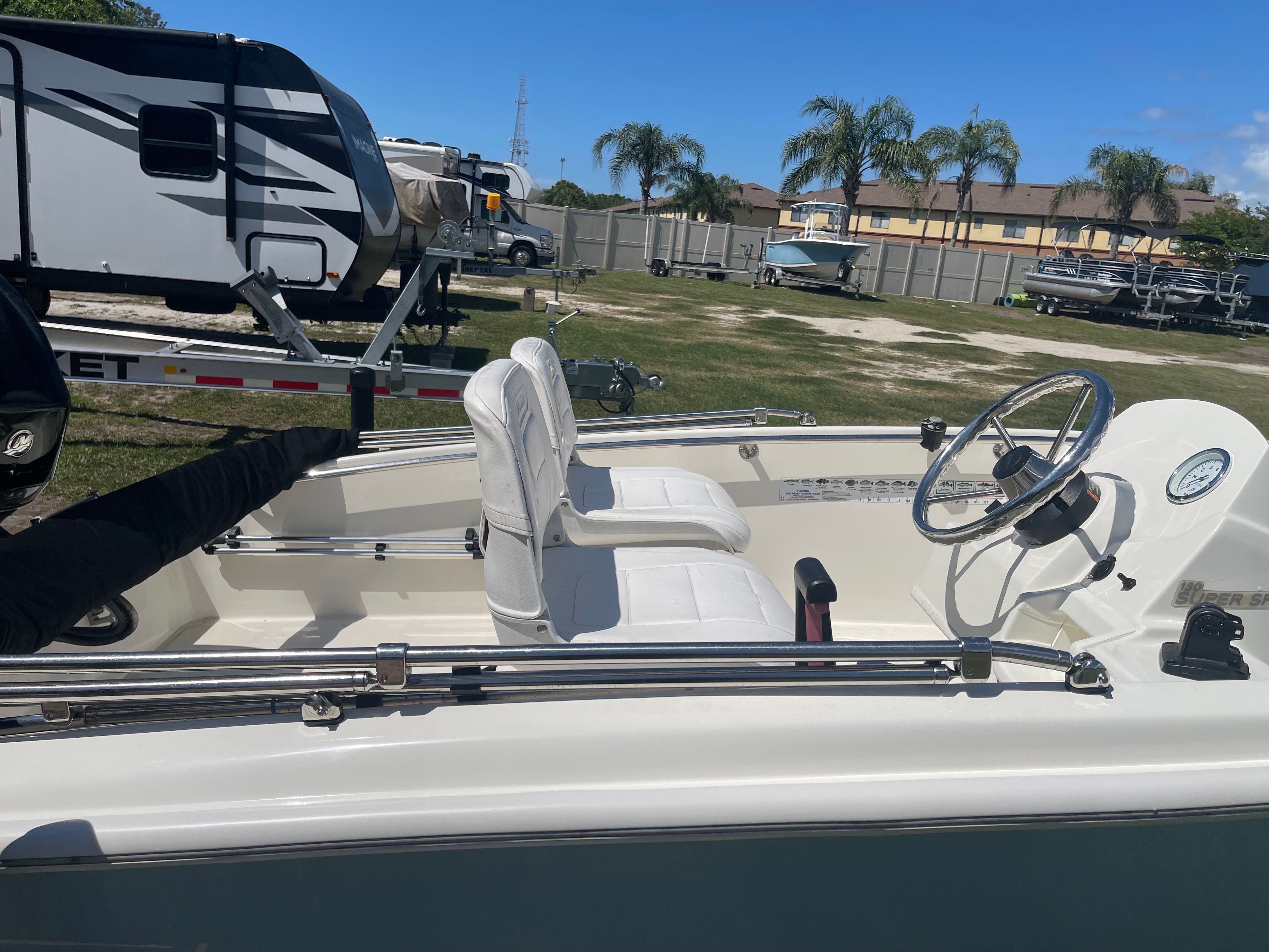 A 2017 Boston Whaler 130 Super Sport with white seats and steering wheel, parked on grass.
