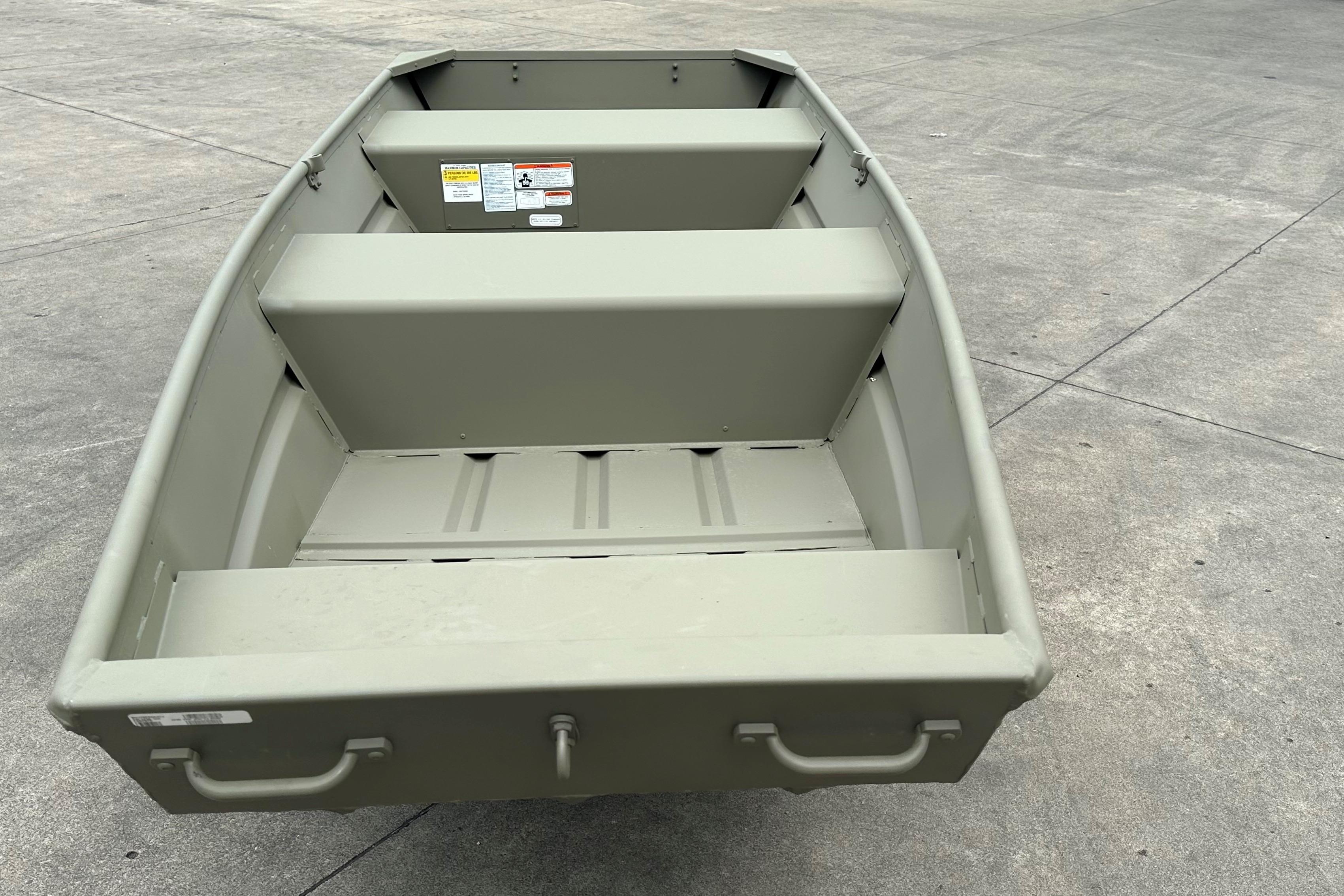 2026 Tracker Grizzly 12 Jon boat on concrete surface, showcasing interior seating and handles.