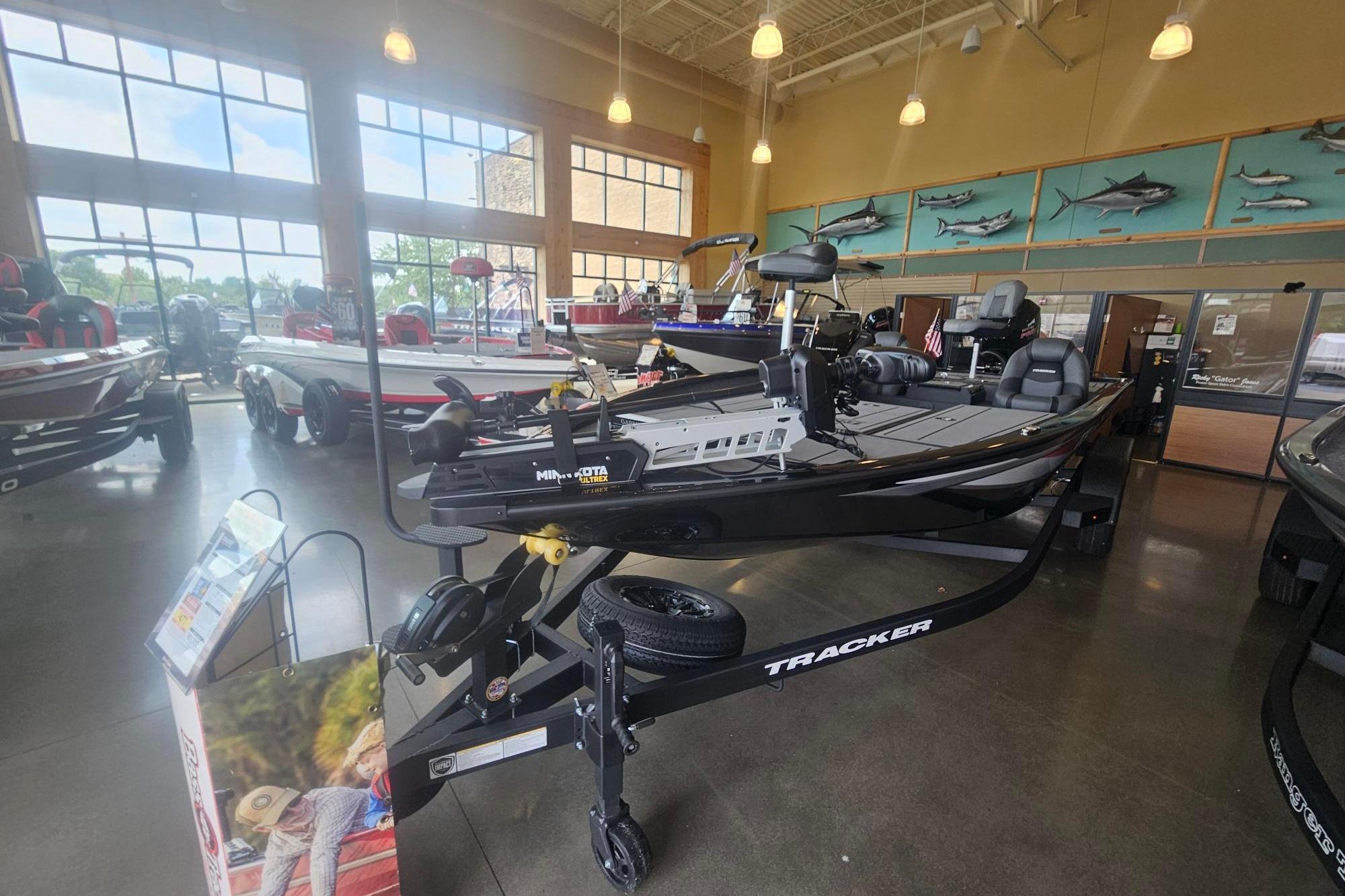 2026 Tracker Savage 215 boat displayed in a showroom with large windows and marine decor.