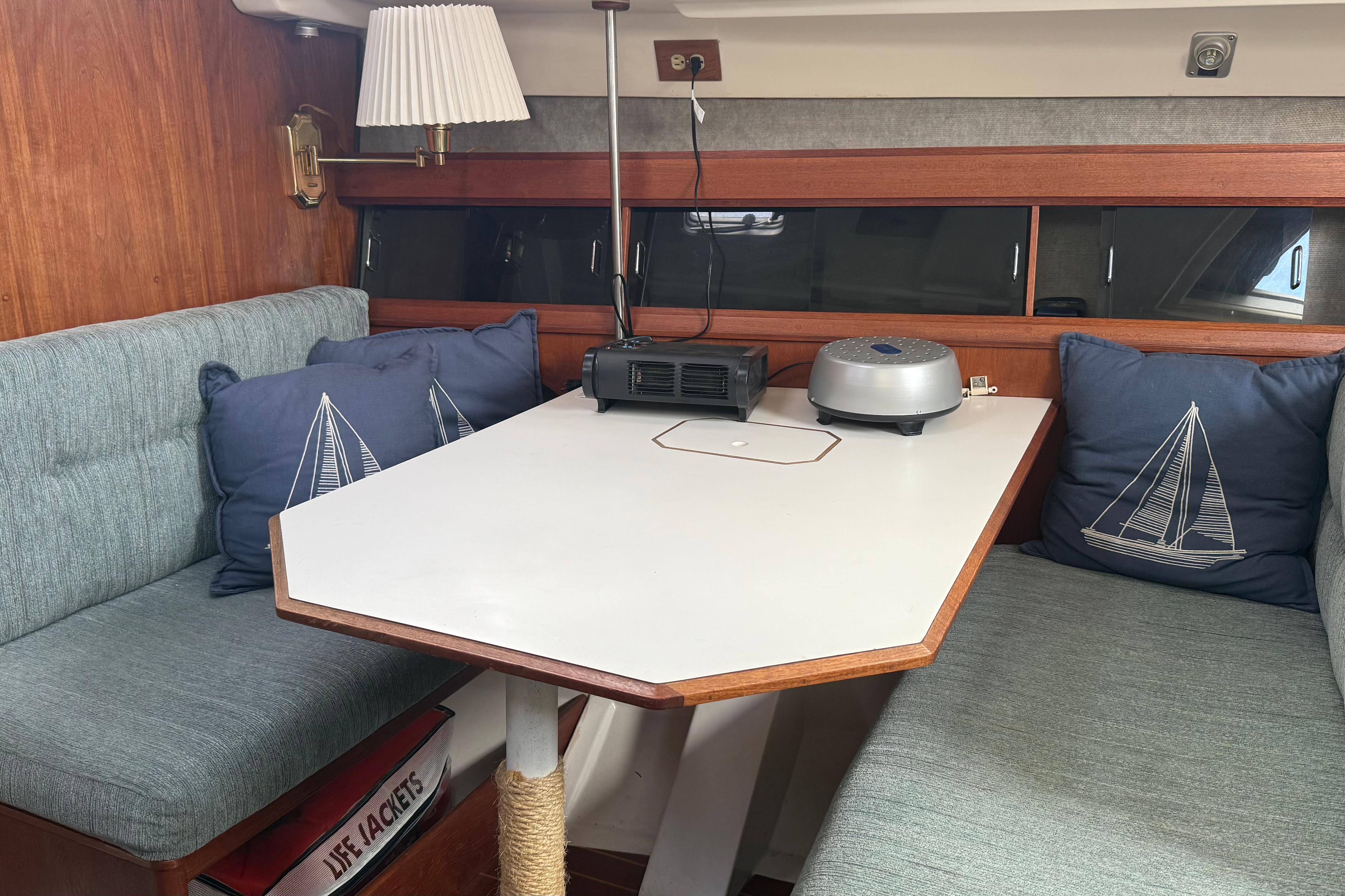 Cozy interior of 1984 Hunter 31 sailboat with table, cushions, and nautical decor.