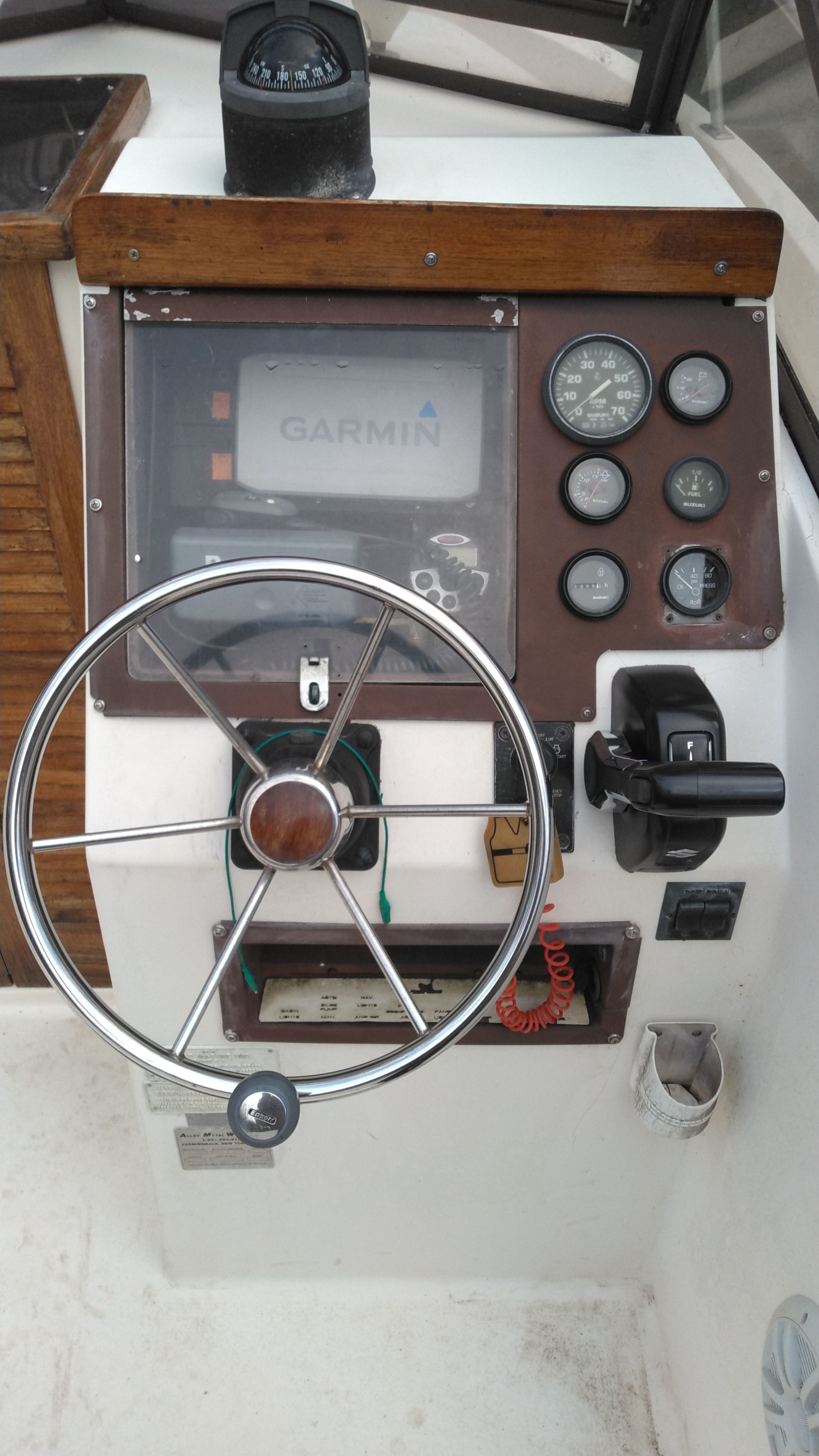 The cockpit of a Mako 240 Walk Around boat with steering wheel, instruments, and Garmin device.
