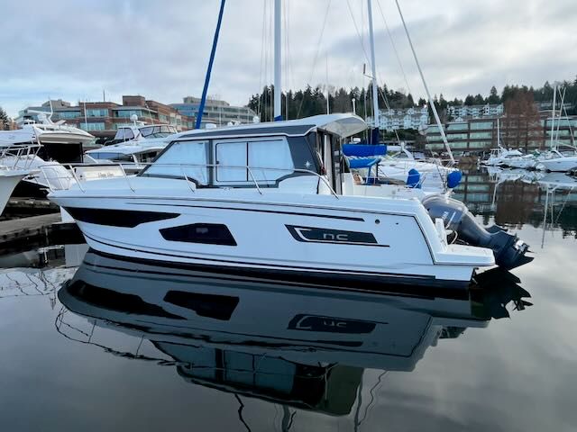 A 2021 Jeanneau NC 1095 is calmly docked in a marina.