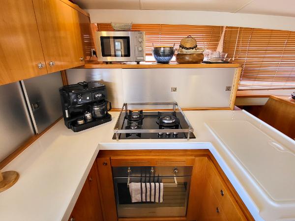 Modern kitchen in a 2009 Catana 65 yacht with stove, oven, and coffee maker.