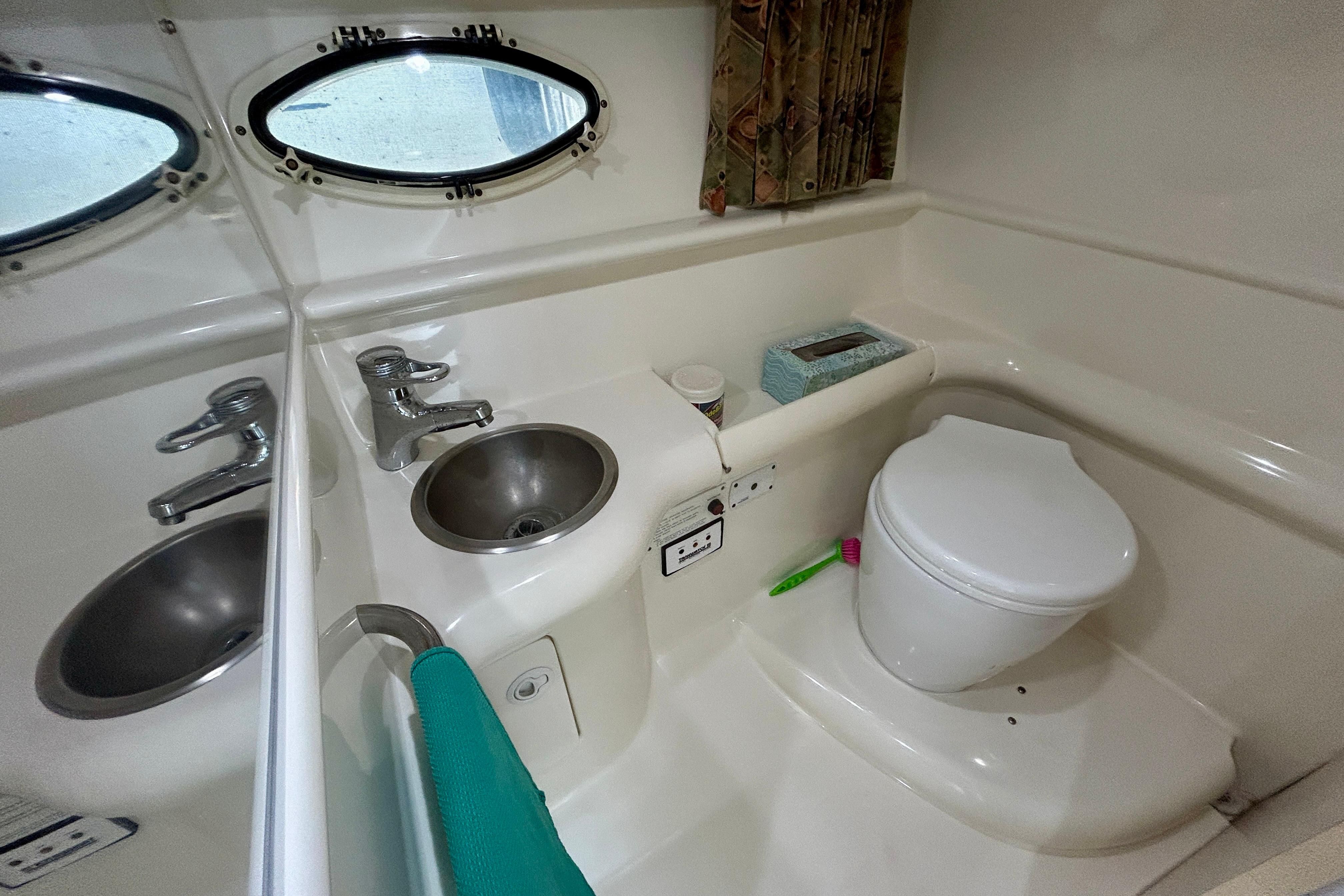 1999 Formula 330 Sun Sport boat bathroom with sink, toilet, and porthole window.