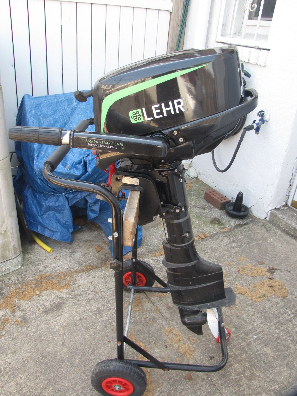 An outboard motor on a wheeled stand, placed on a concrete floor.
