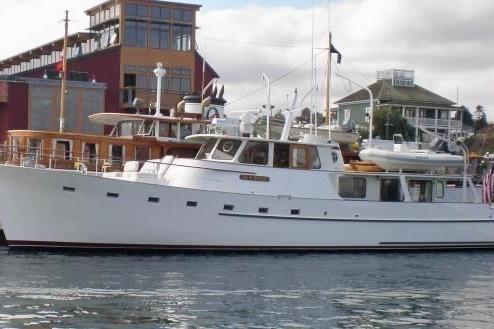1958 Blanchard Pilothouse yacht docked near colorful waterfront buildings.