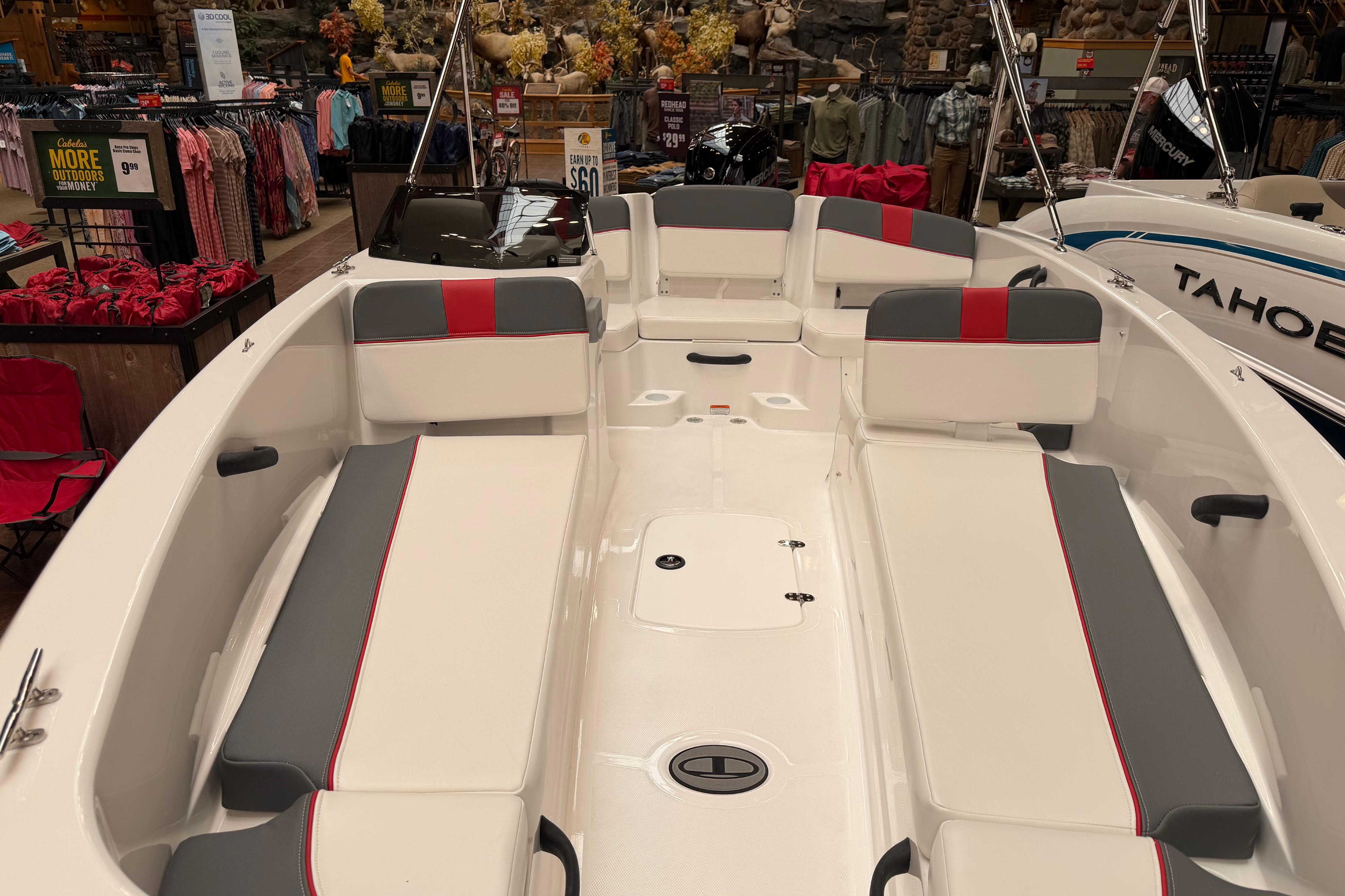 2026 Tahoe T18 boat interior with gray and red seating, displayed in a showroom.