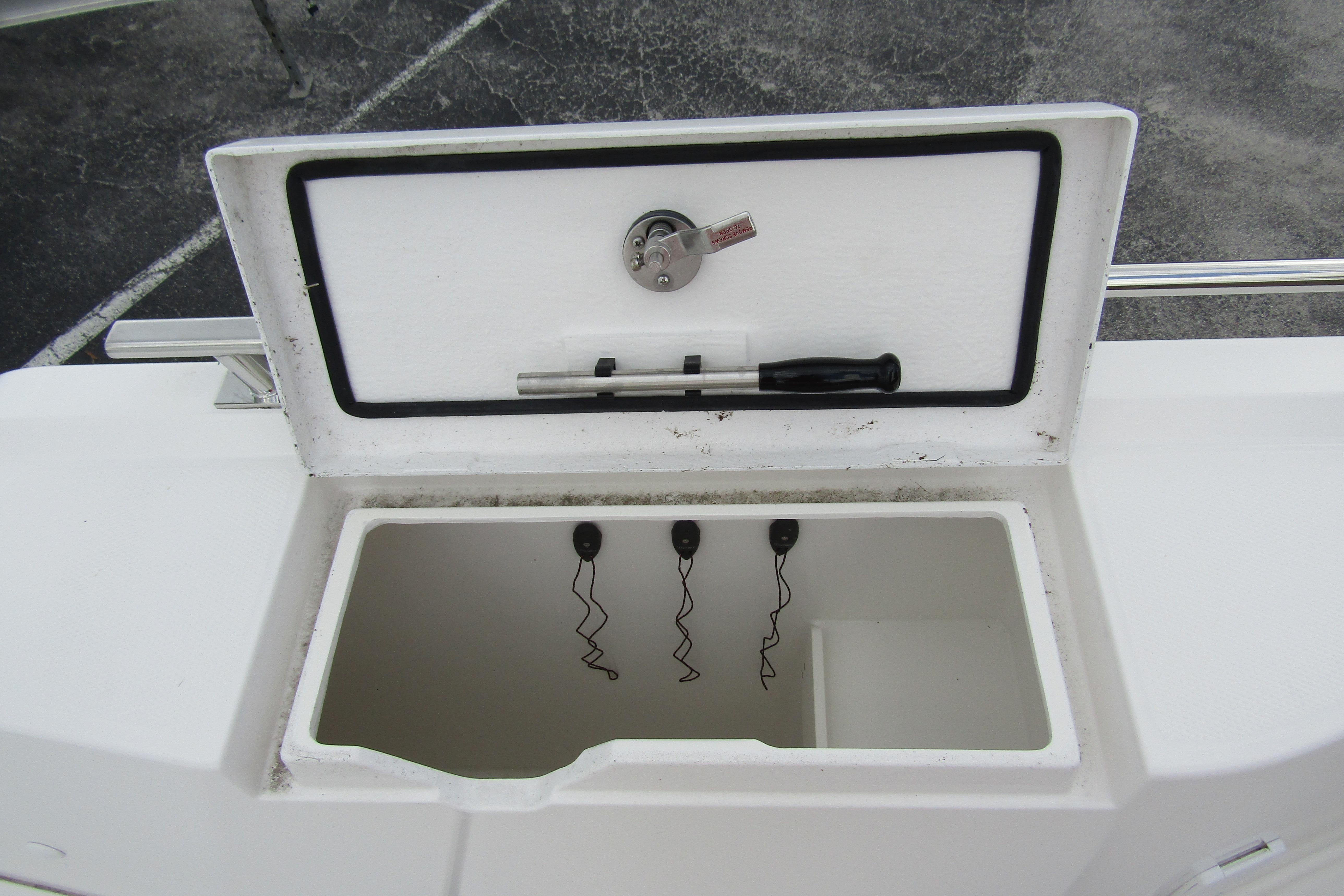 Open storage compartment on 2025 Nimbus Tender 11 boat, featuring a lock and tools.