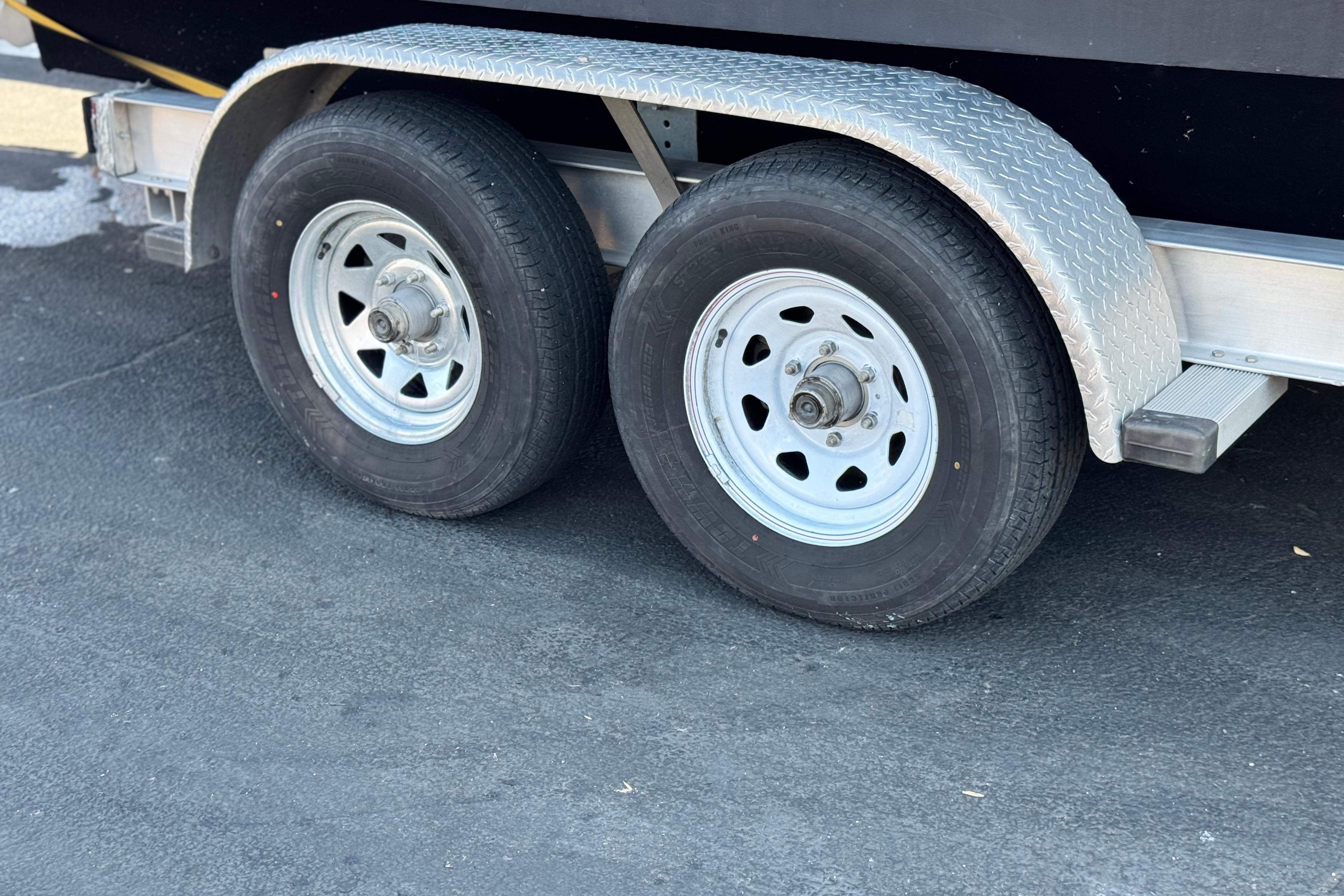 Trailer wheels of a 2008 Cobalt 262 boat on asphalt surface.