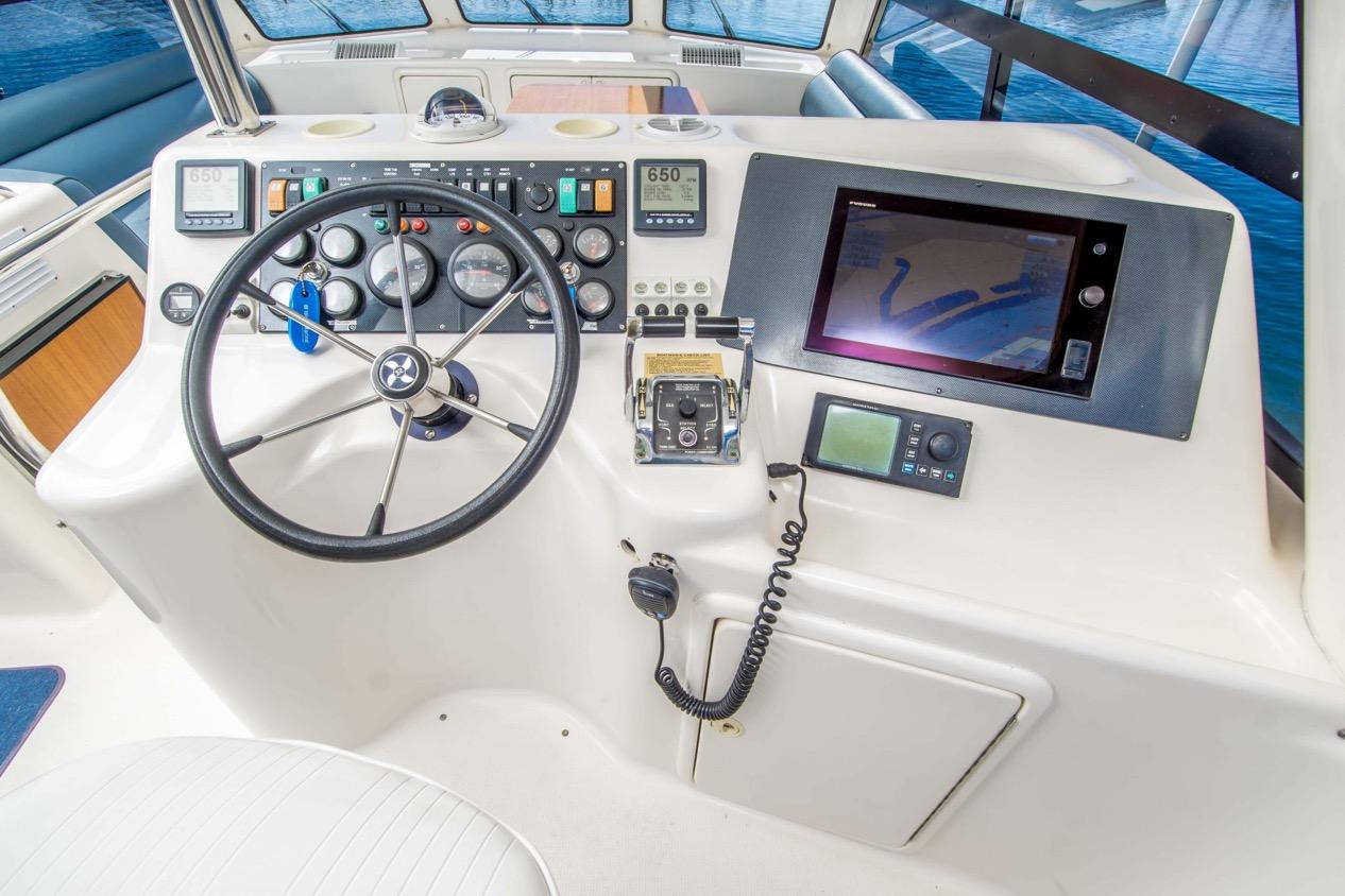 Control panel of 2000 Riviera 48 Enclosed Flybridge with steering wheel and navigation equipment.