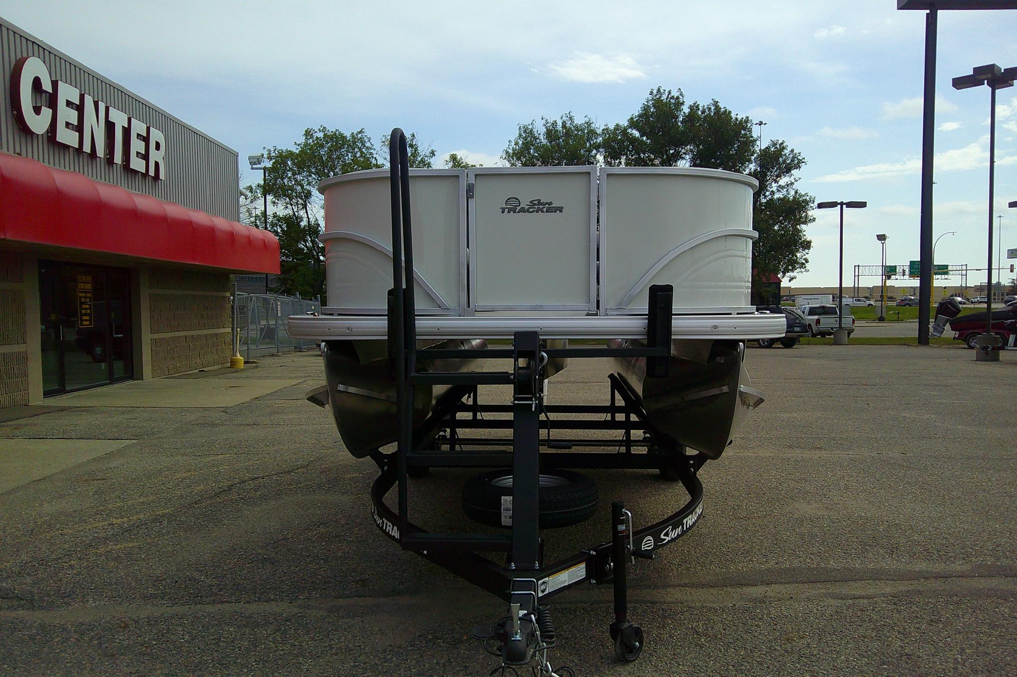2026 Sun Tracker Party Barge 16 DLX pontoon boat on trailer outside dealership.