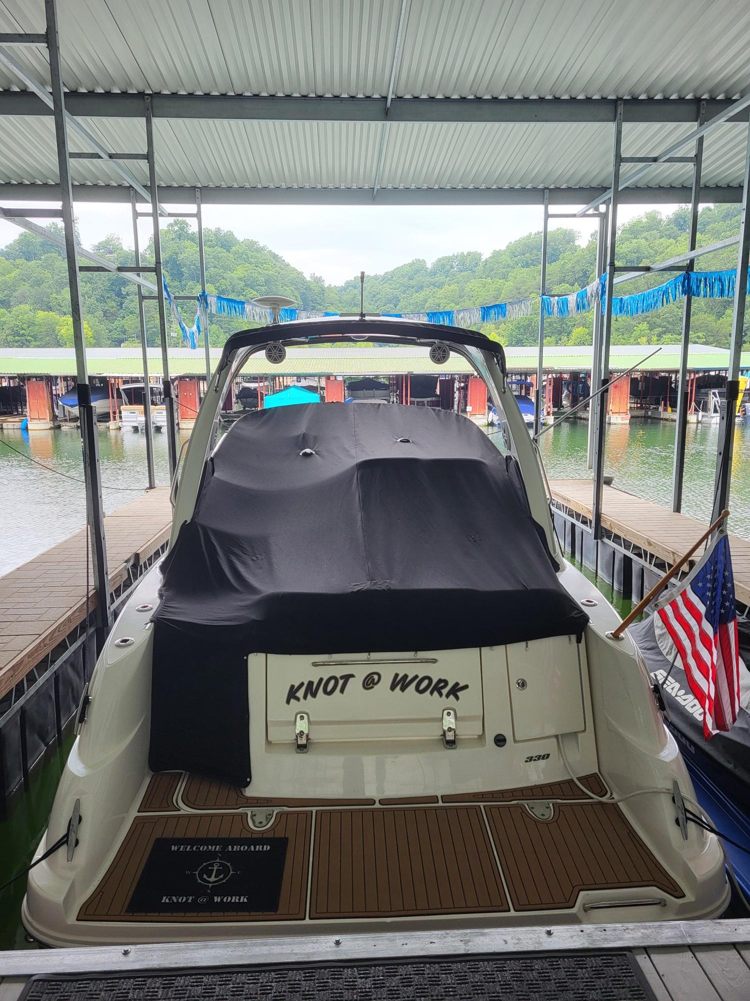 2009 Sea Ray 310 Sundancer docked, covered, with "Knot @ Work" name and American flag.