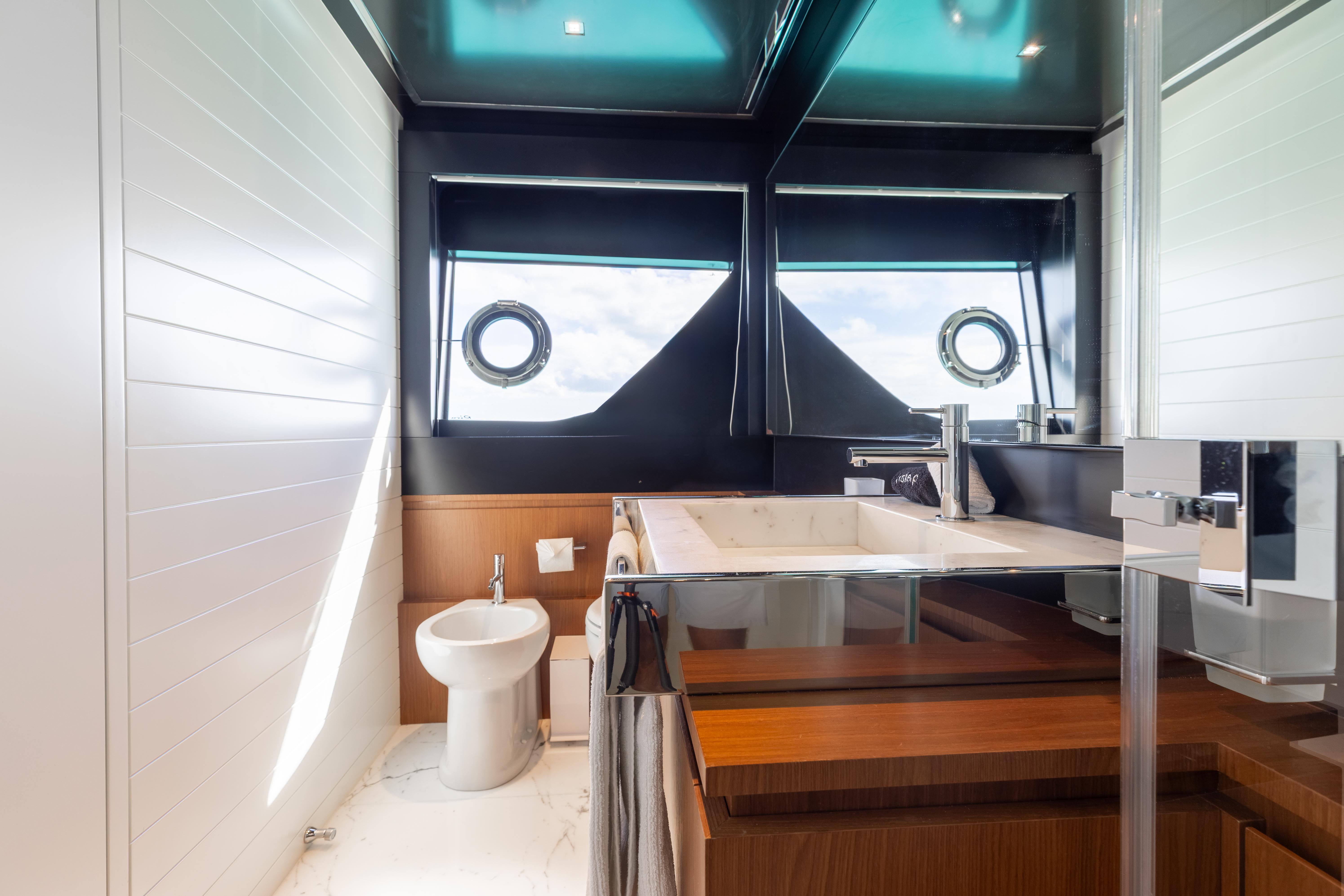 Luxurious bathroom interior of 2020 Riva 90 Argo yacht with modern fixtures and porthole windows.