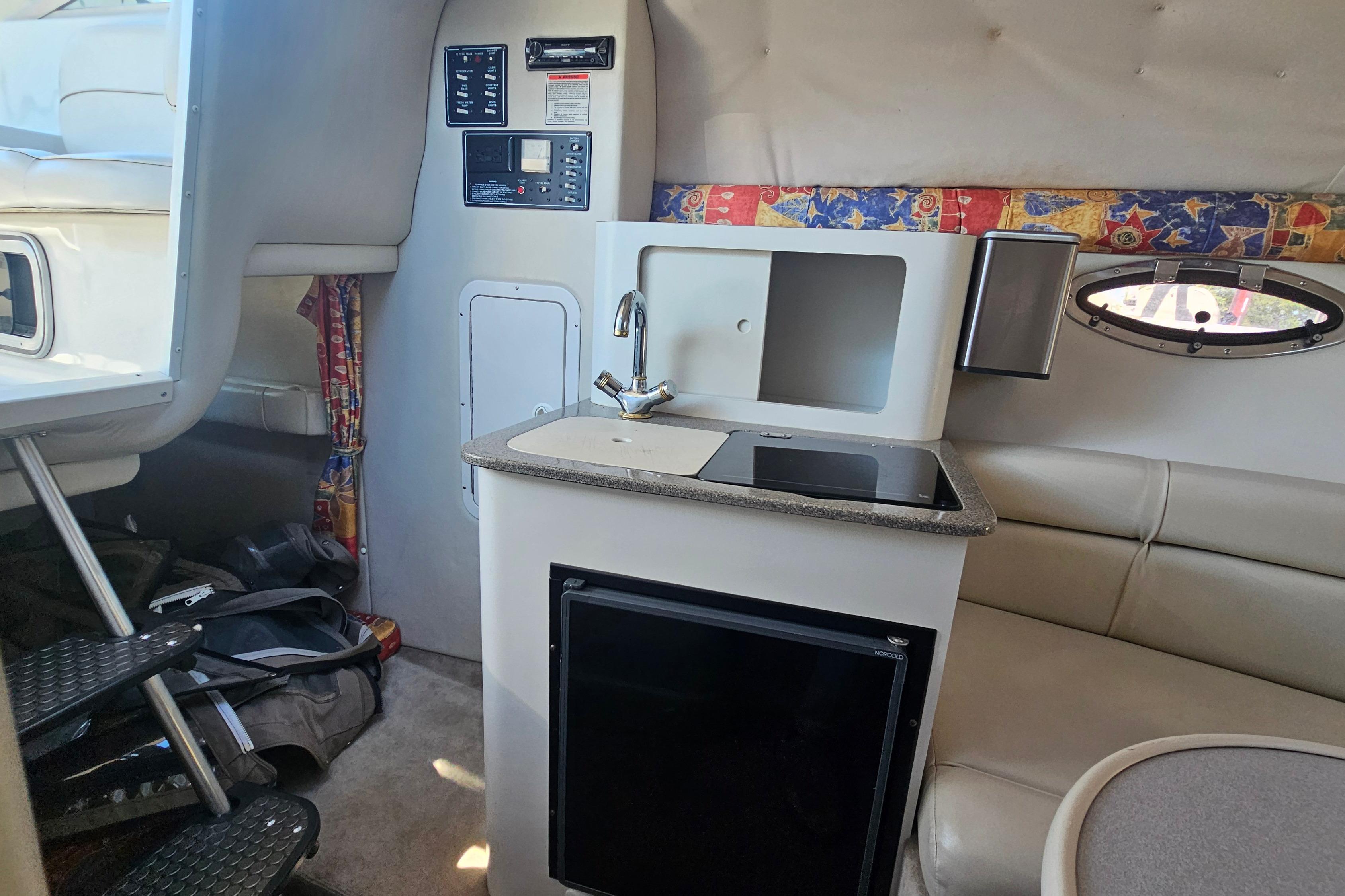 Interior of 2000 Crownline 242 CR boat featuring kitchenette and seating area.
