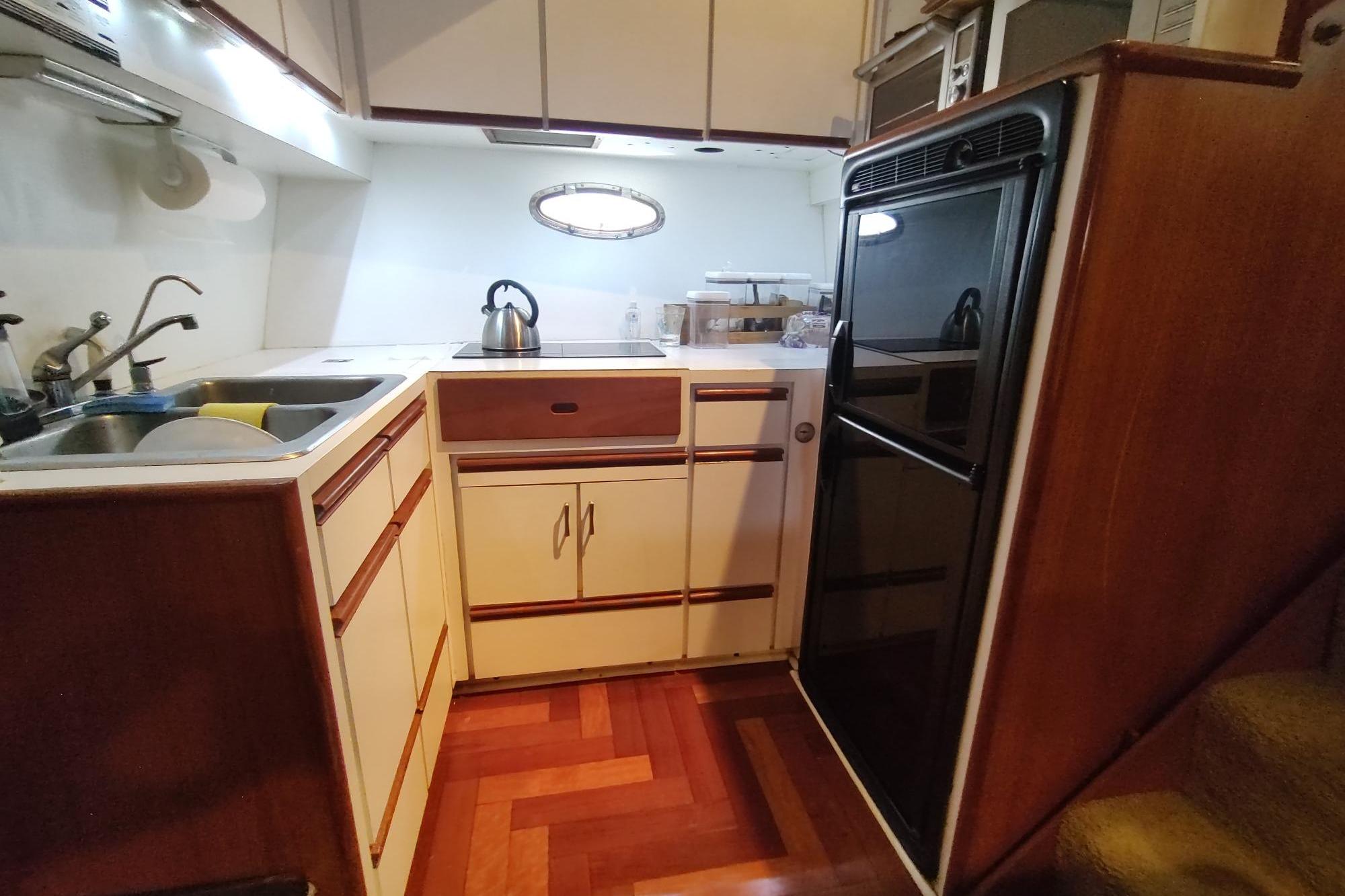 Compact kitchen in 1989 Hyatt Double Cabin Motoryacht with wood flooring and modern appliances.