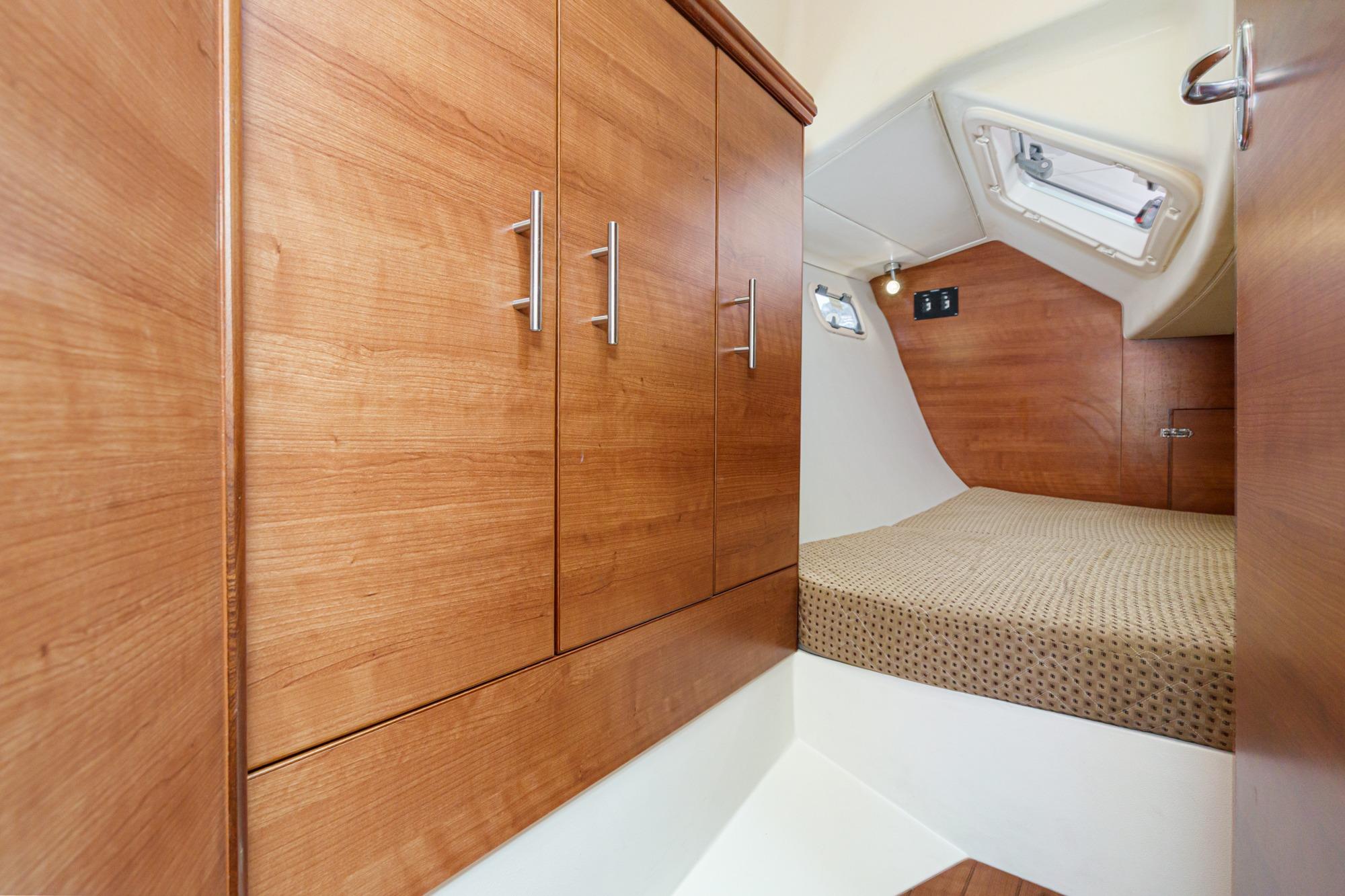 Interior cabin of 2015 Hunter 33 sailboat with wooden cabinetry and cozy bed.