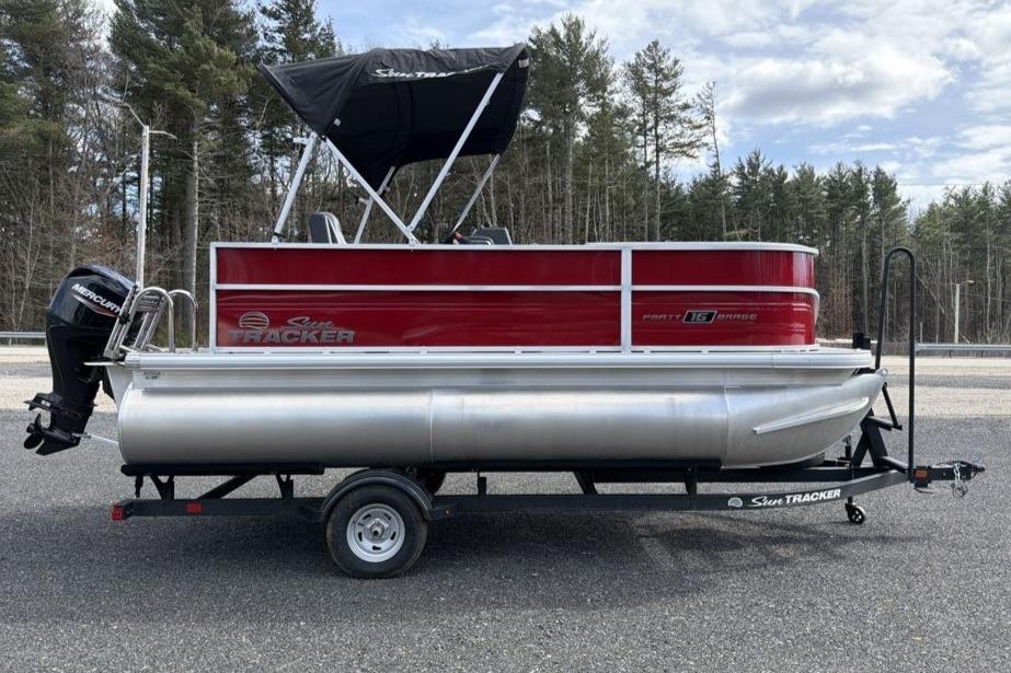 2026 Sun Tracker Party Barge 16 DLX pontoon boat on trailer, red and silver design.
