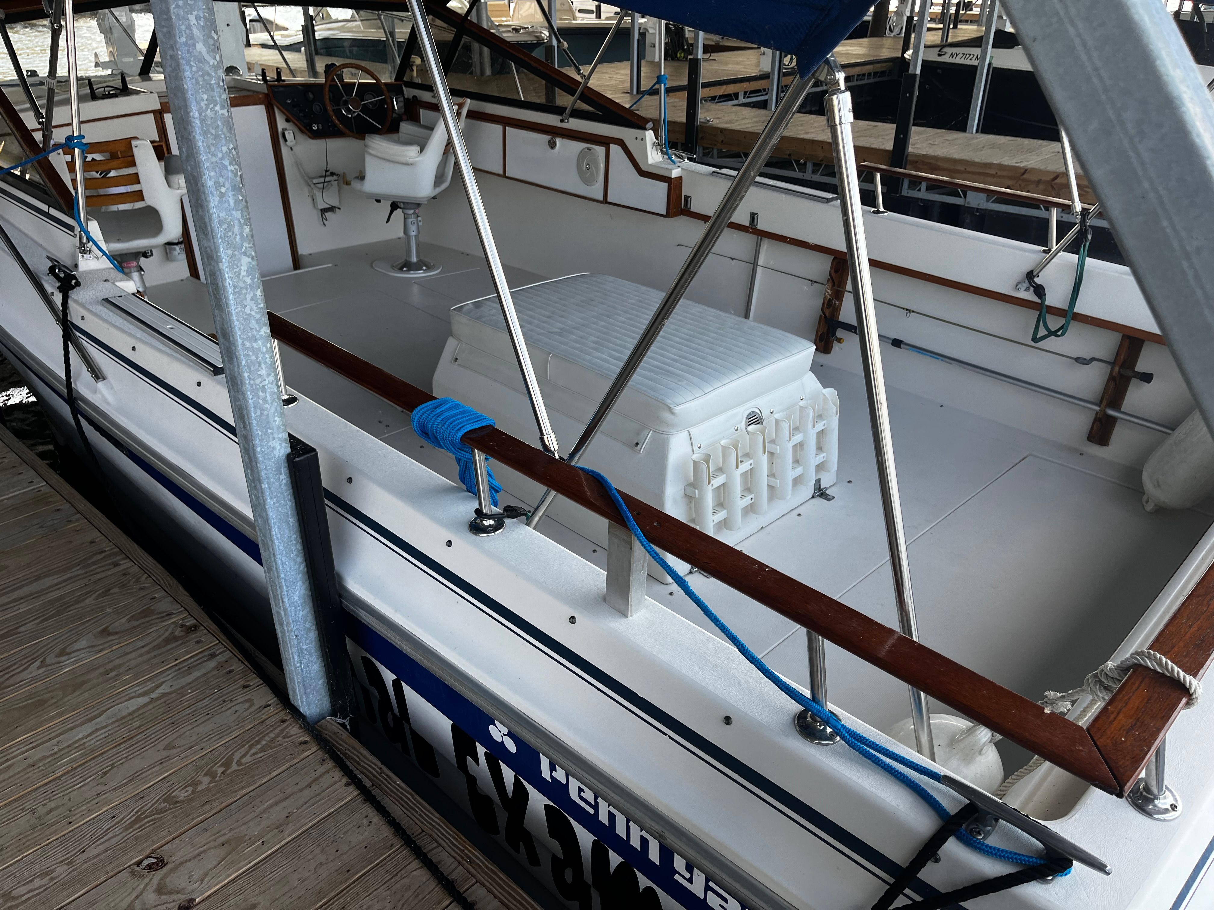 The image shows a 1981 Penn Yan Sportsman boat at a dock. It features white seating and a blue rope.