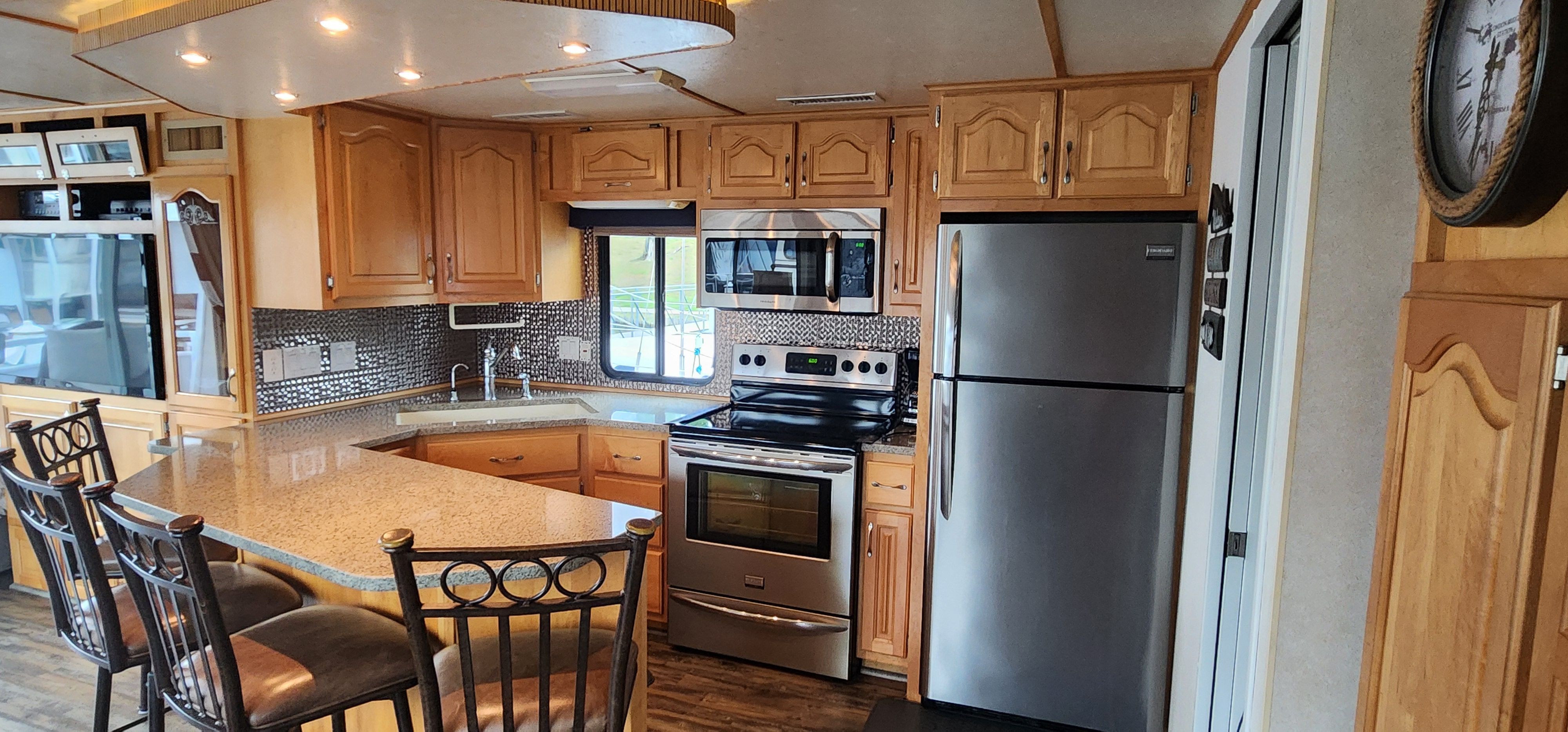 The kitchen of a yacht with wooden cabinets, stainless steel appliances, and a granite countertop.
