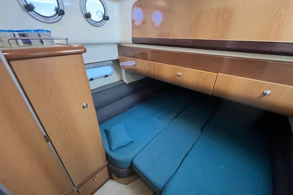 1999 Sealine F44 yacht cabin with blue bedding and wooden storage cabinets.
