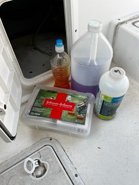 A first aid kit and cleaning supplies are on the floor of a boat.
