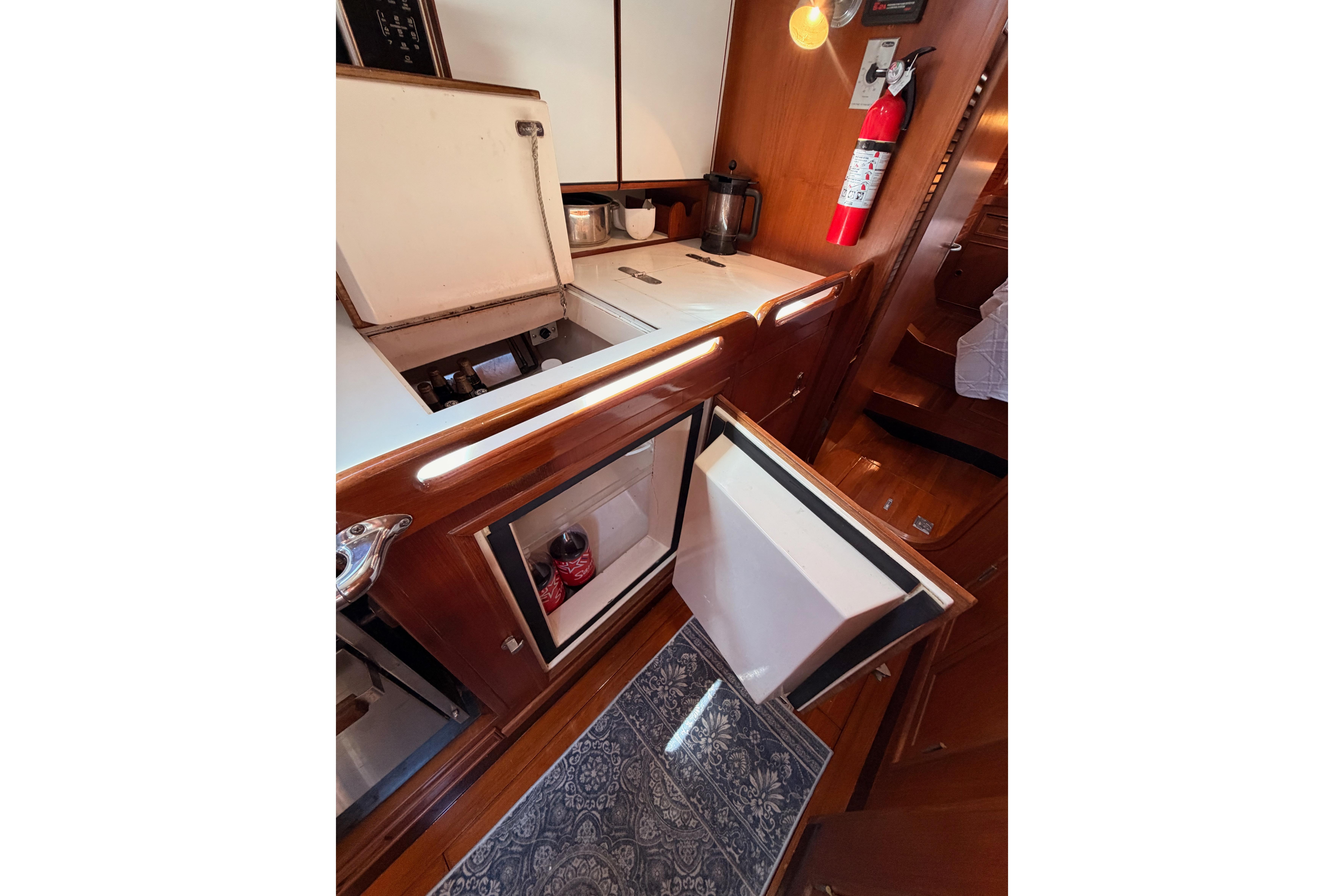 Interior of 1991 Hylas 51 yacht kitchen with open fridge and fire extinguisher.