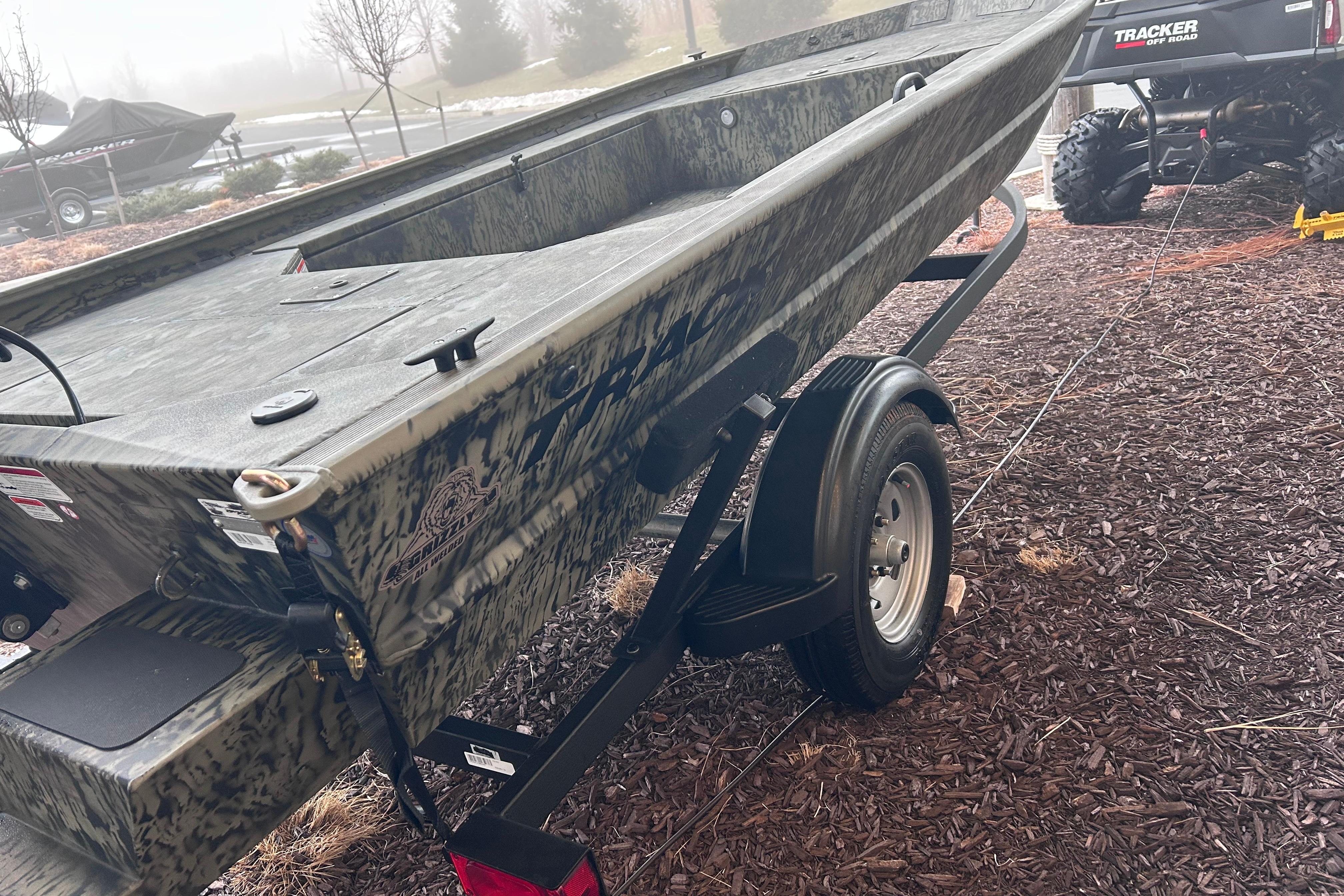 2026 Tracker Grizzly 1654 T Sportsman boat on trailer, outdoors in a misty setting.