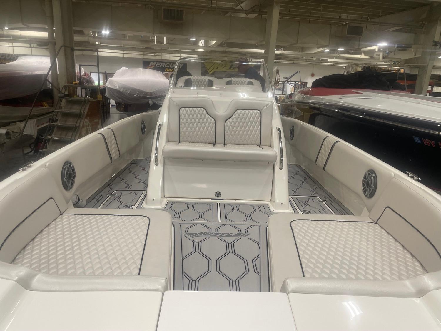 2025 Hustler 25 C3 Speedfish boat interior with white cushioned seating and geometric flooring.