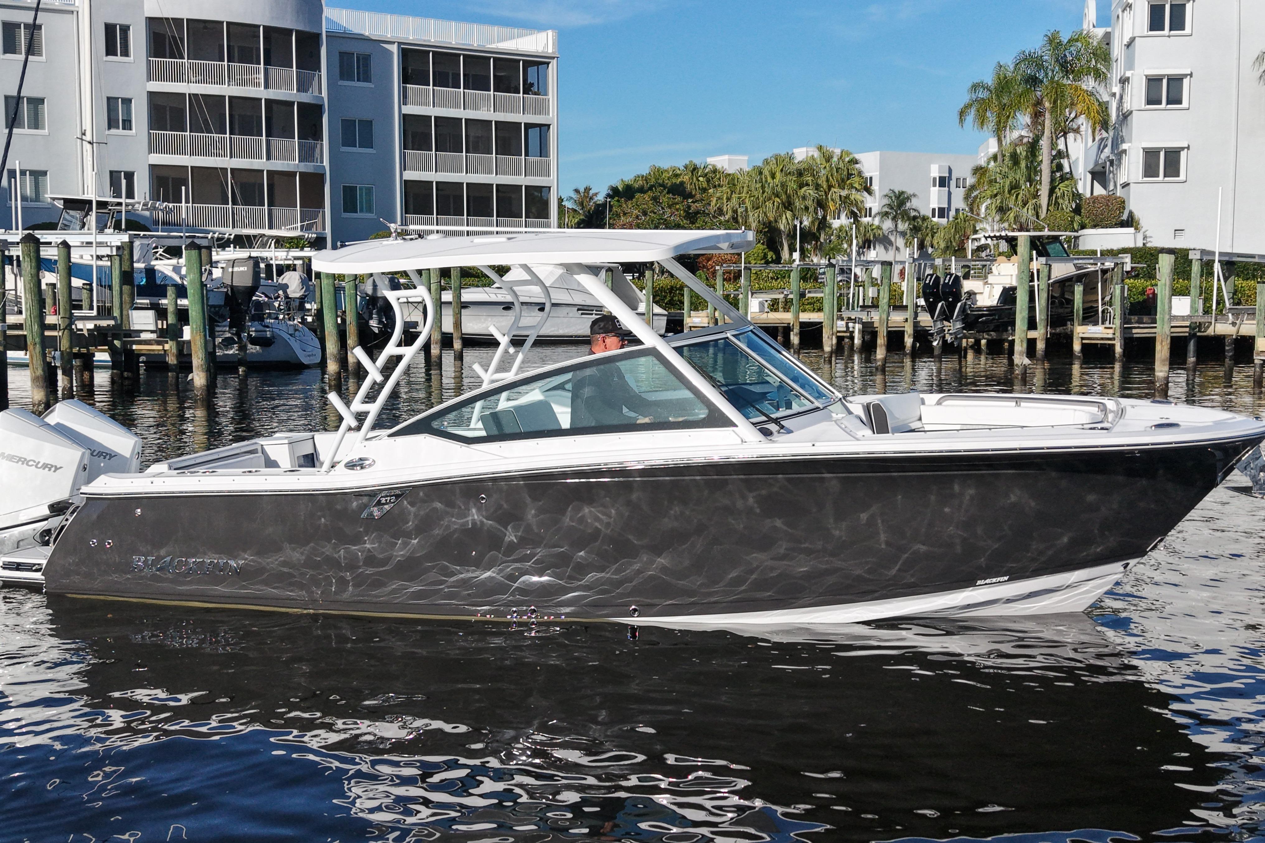 2025 Blackfin 272 DC boat docked near waterfront buildings.