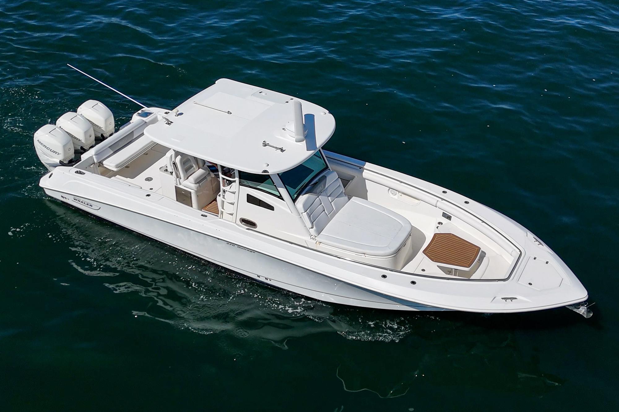 2015 Boston Whaler 370 Outrage boat on open water, featuring triple outboard engines.