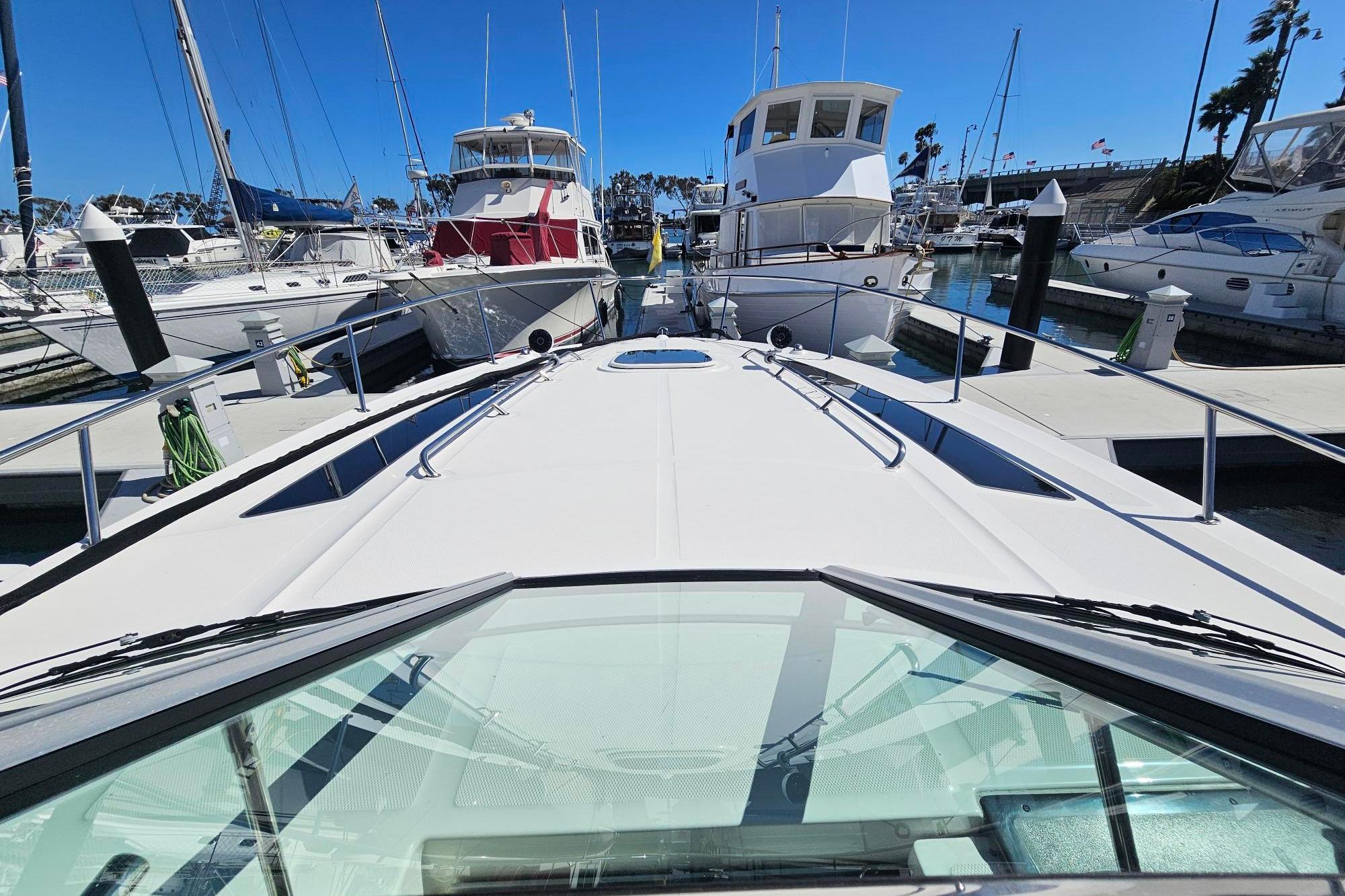 2016 Sea Ray Sundancer 350 docked at marina, surrounded by other boats under clear blue sky.