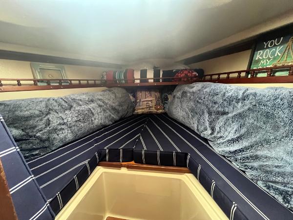 Cozy interior of a 1980 Catalina 30 sailboat with plush bedding and decorative pillows.