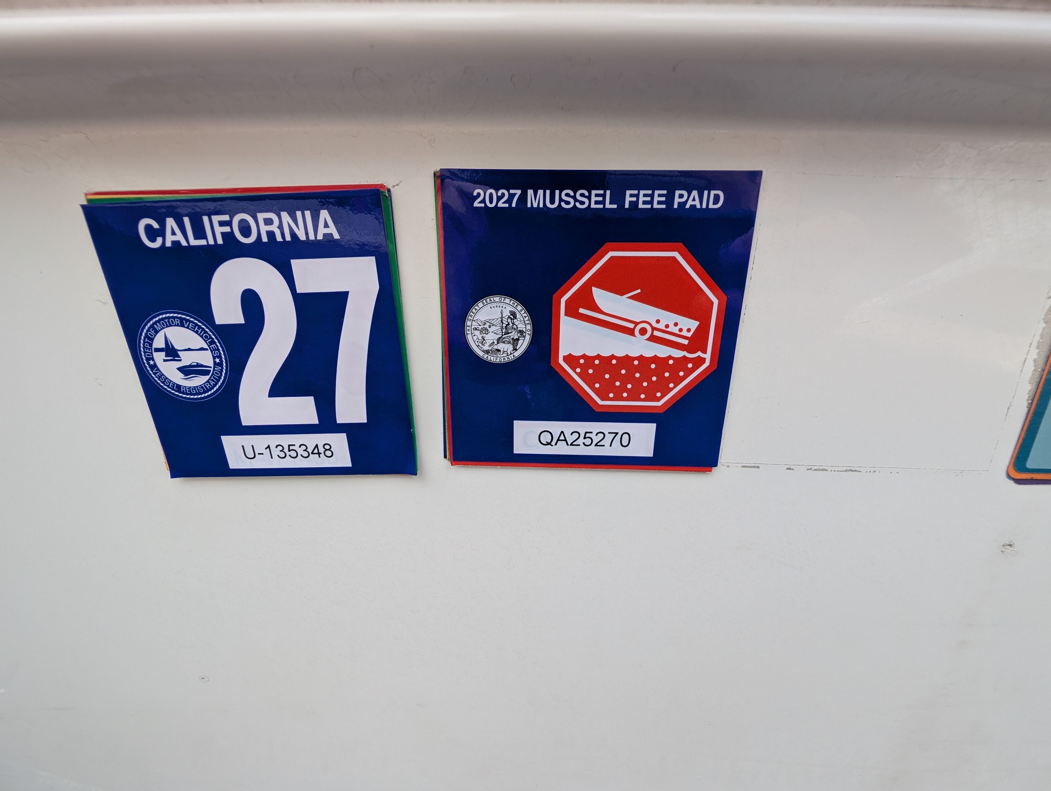 California boat registration and mussel fee stickers on a boat.