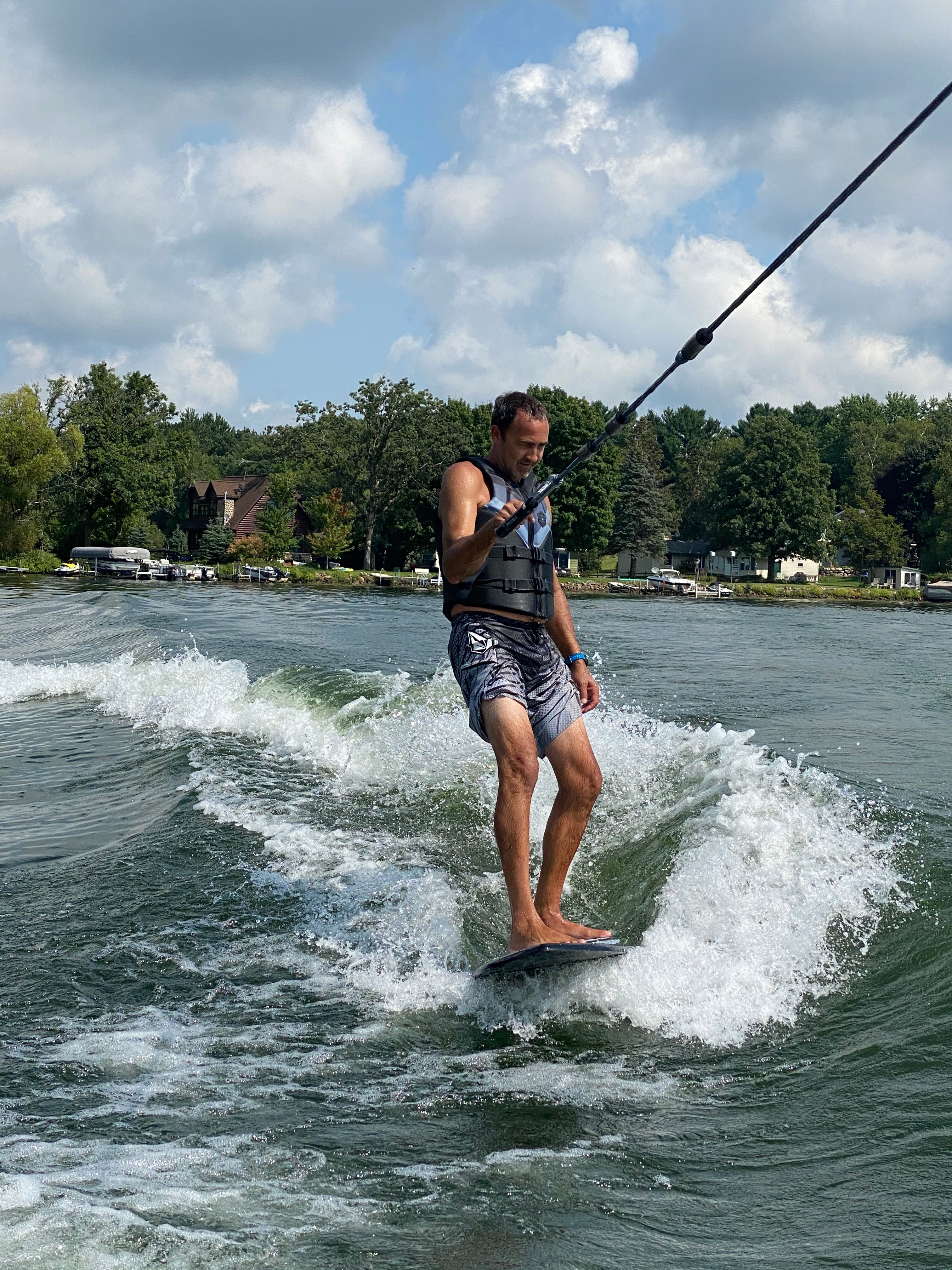 A man surfs behind a MasterCraft NXT22 boat on a lake.