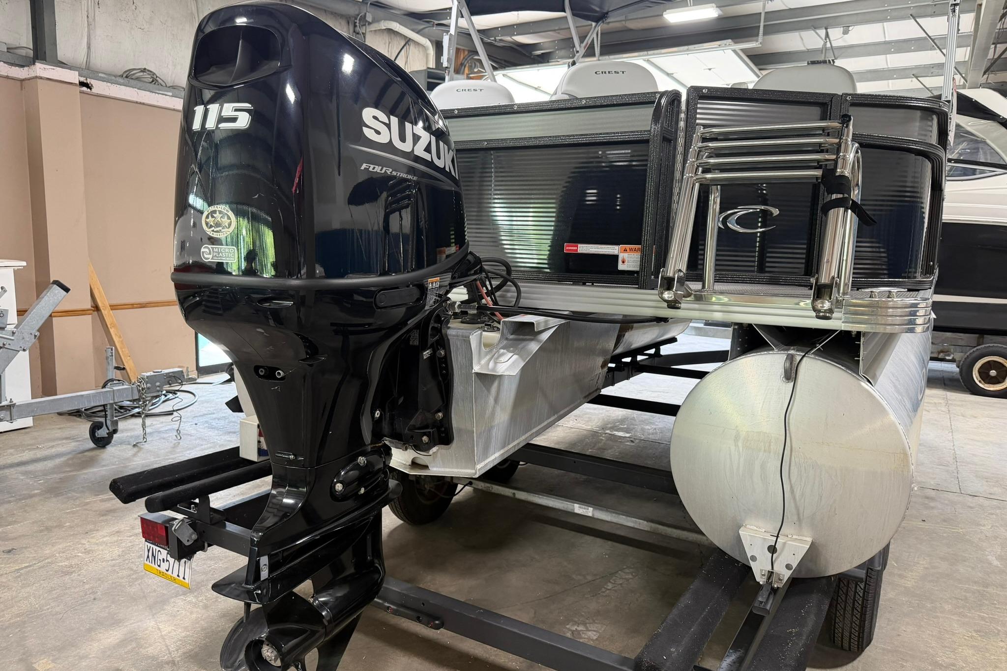 2023 Crest Classic LX 200 pontoon boat with Suzuki 115 outboard motor in a garage.