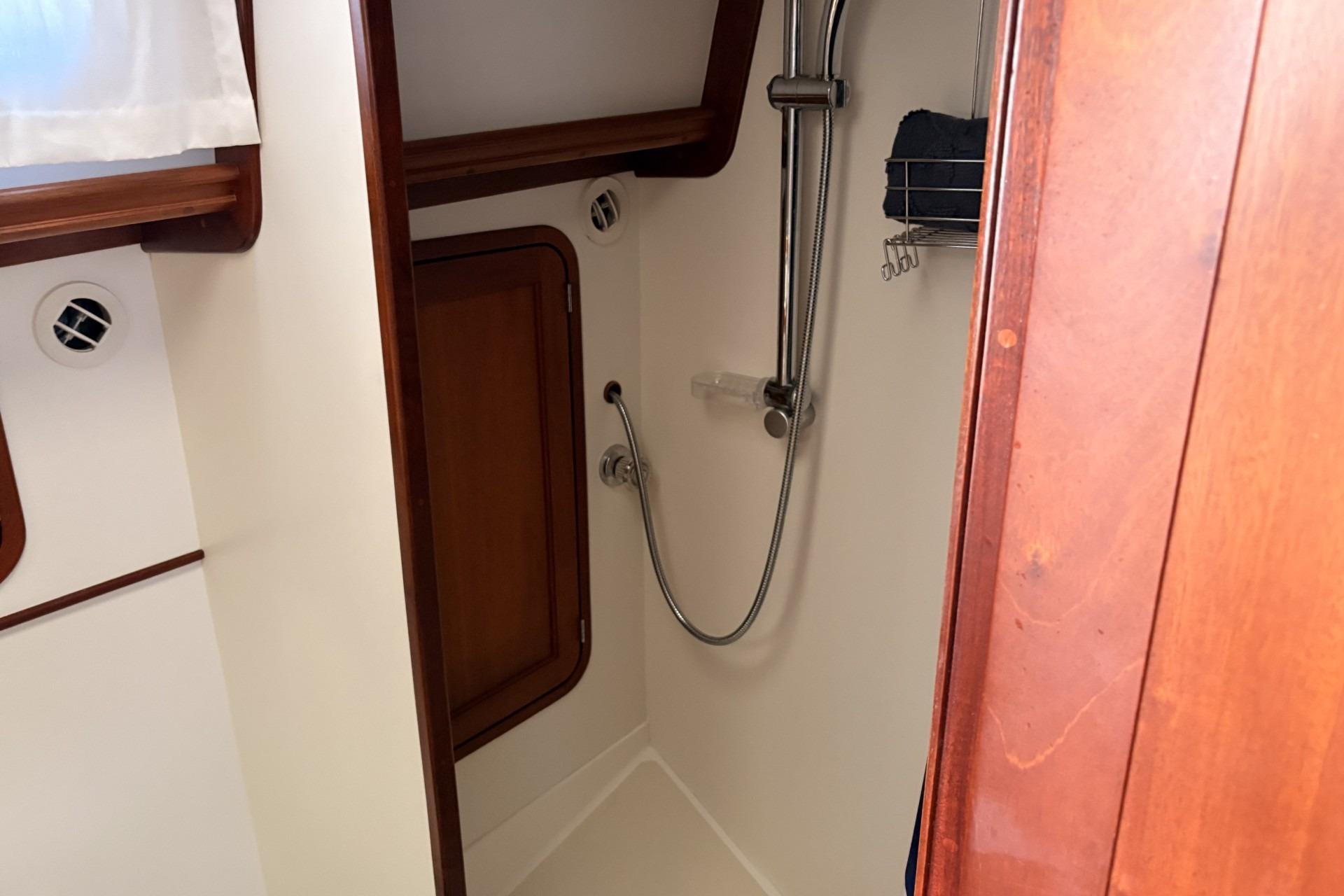 Compact wooden bathroom with showerhead and storage cabinet on a boat.