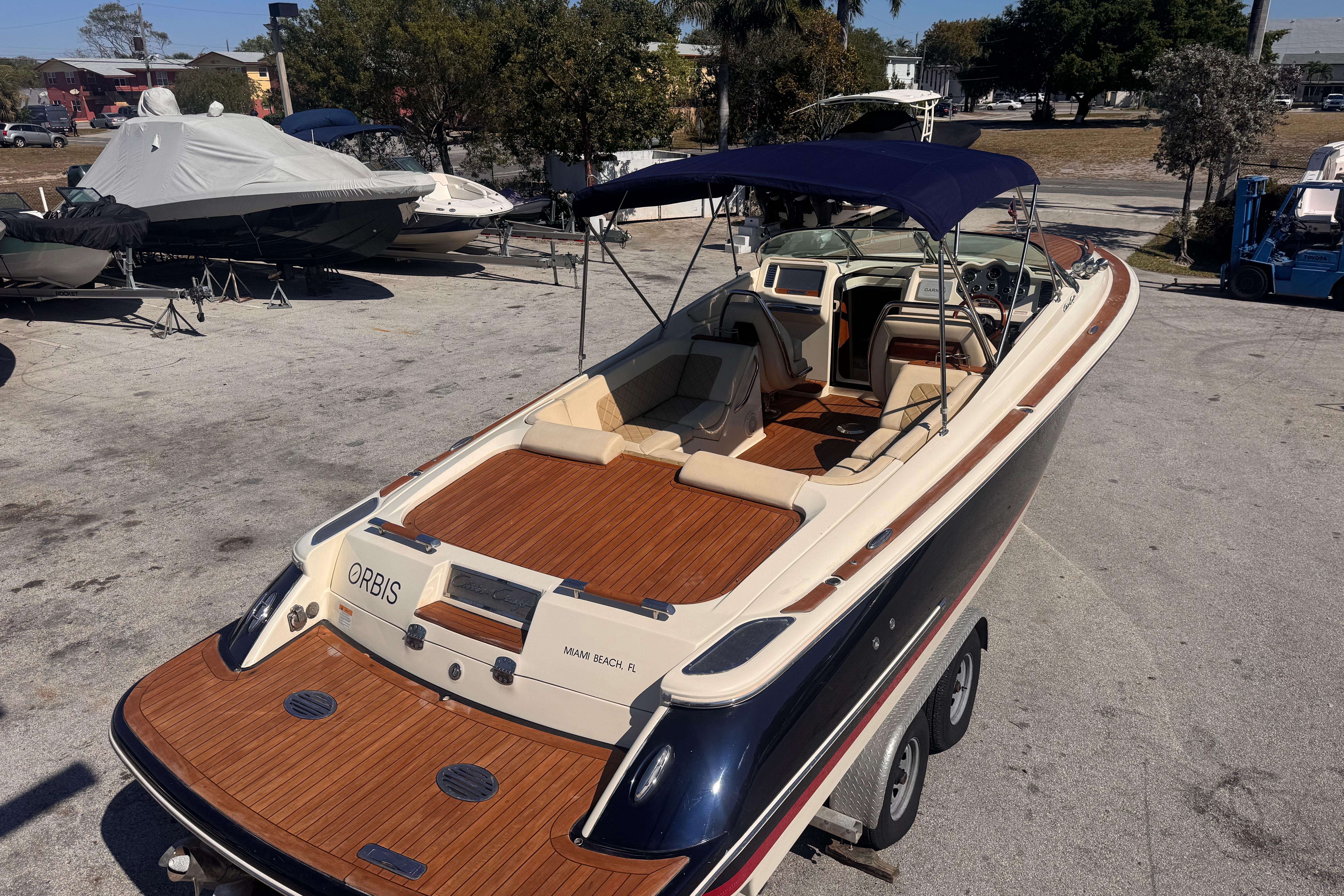2019 Chris-Craft Corsair 30 boat with wooden deck and canopy, parked on a trailer.