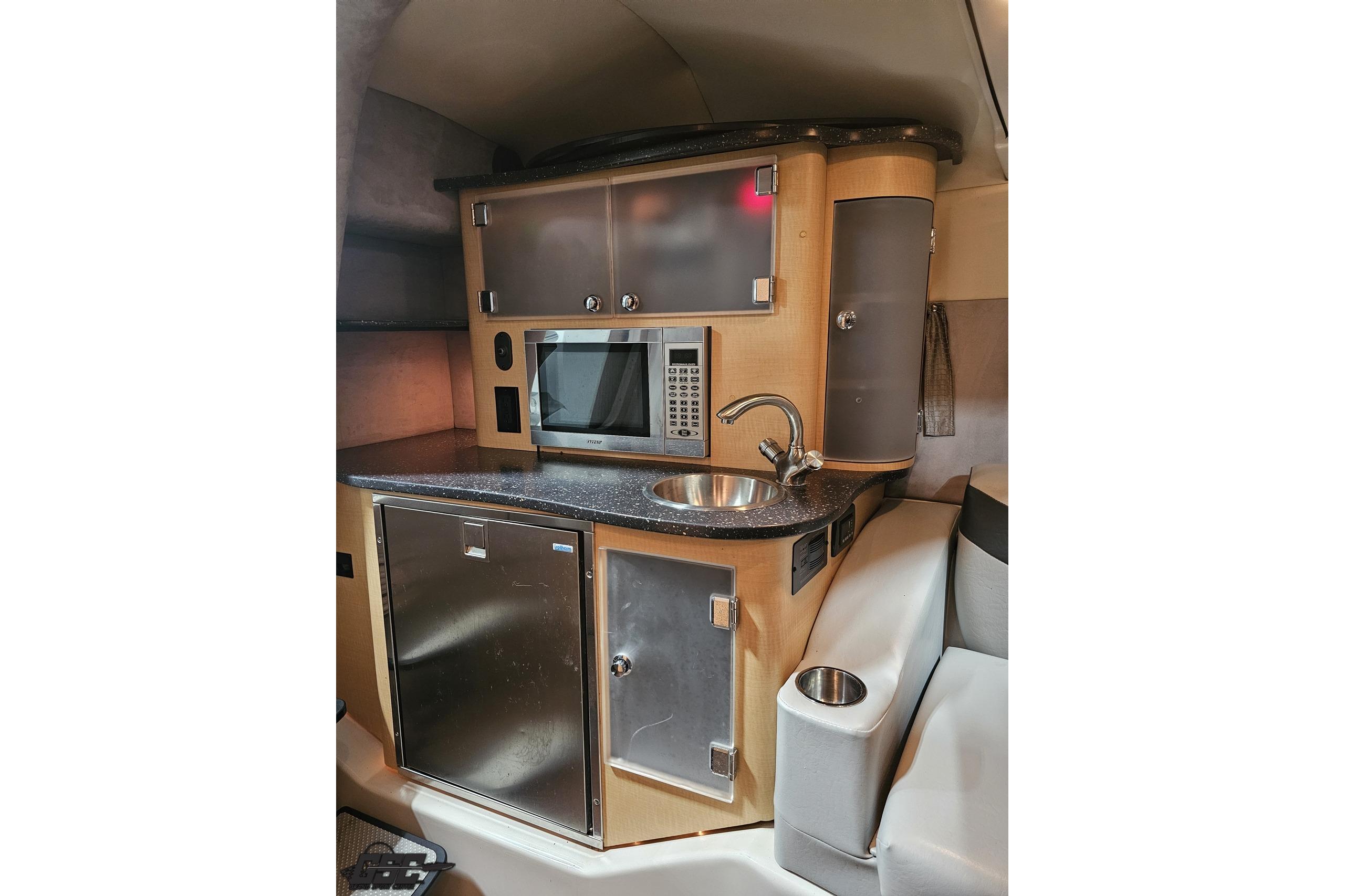Compact kitchenette in 2008 Baja 335 Performance boat with microwave, sink, and storage.