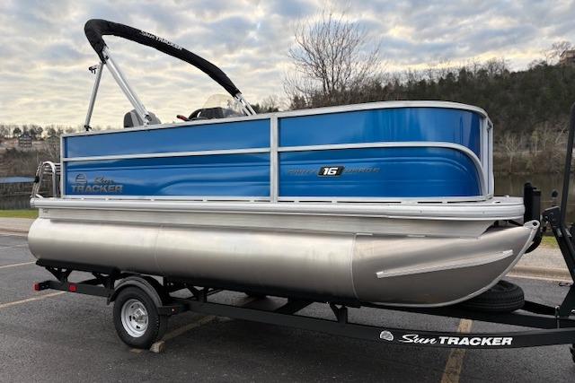2026 Sun Tracker Party Barge 16 DLX pontoon boat on trailer, blue and silver design.