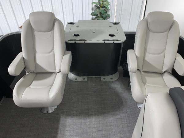 2024 Starcraft EX22 FD boat interior with two white captain chairs and a central table.