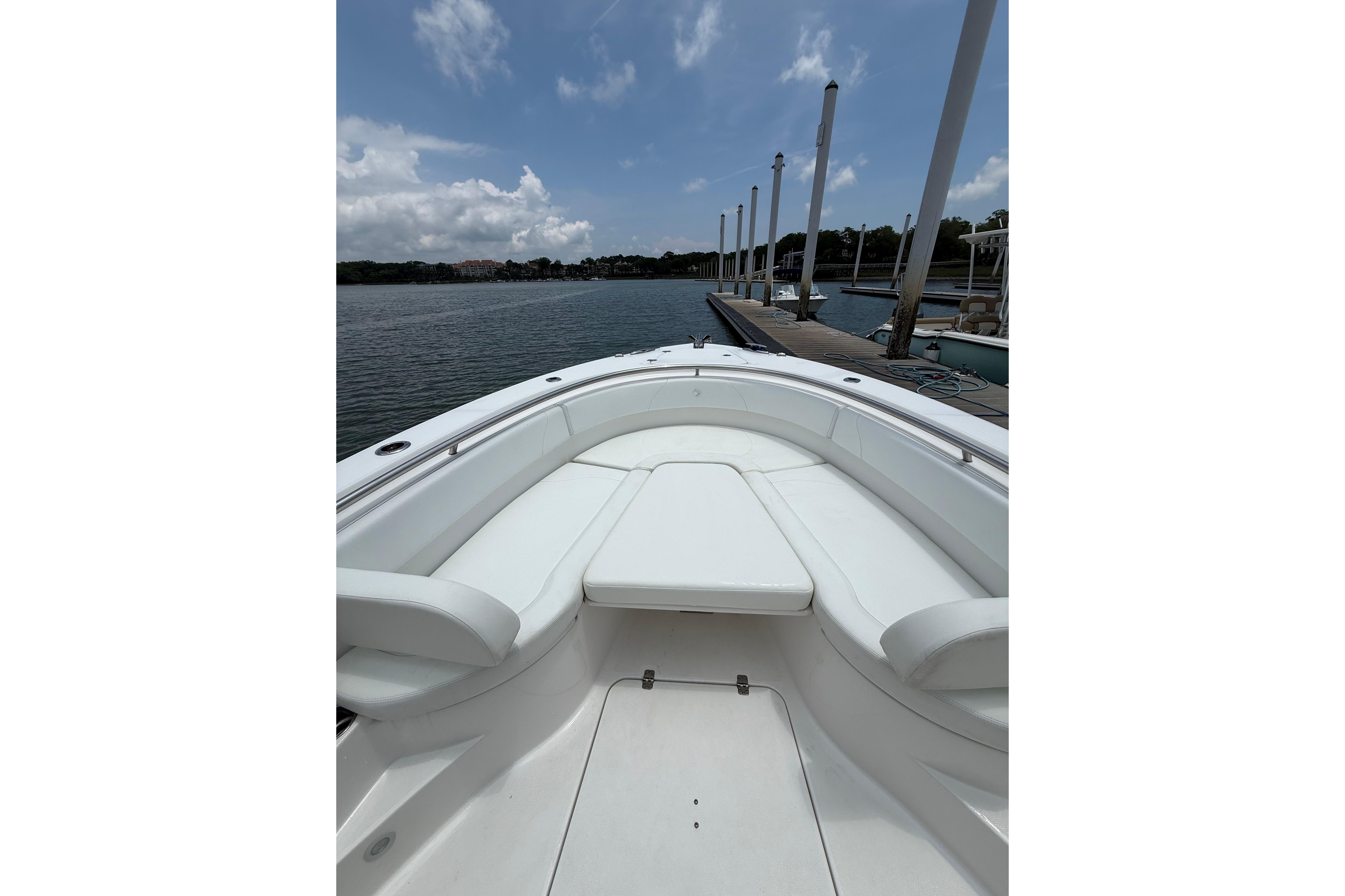 2018 Edgewater 320CC boat interior with white seating, docked by a calm waterfront.