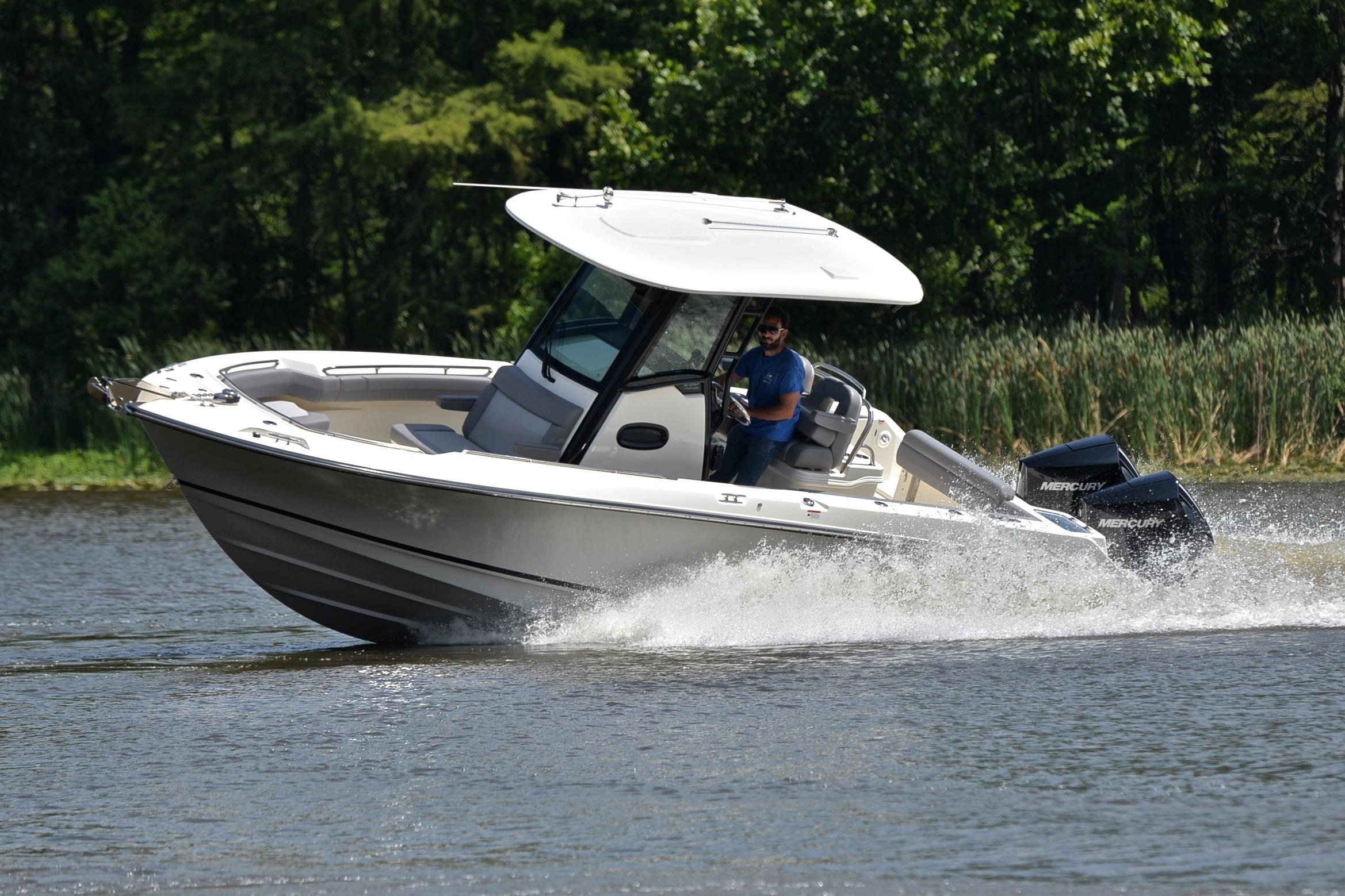2024 Boston Whaler 250 Outrage cruising on a lake with lush greenery.