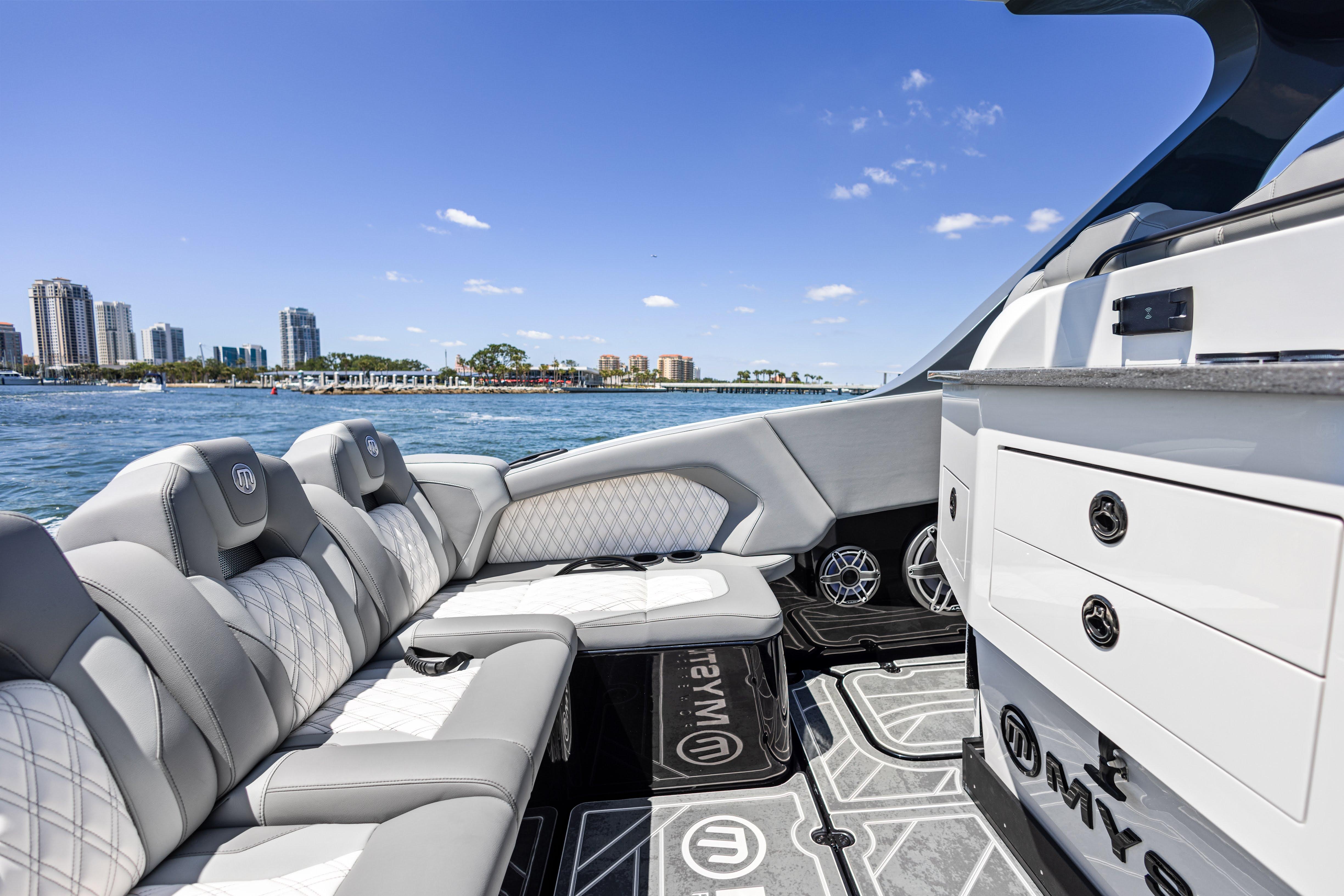Luxurious 2026 Mystic Powerboats M4200 interior with plush seating, city skyline in background.