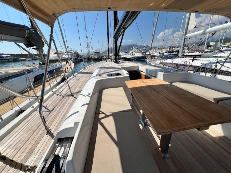 2023 Solaris 50 yacht deck with wooden table, docked in a marina under clear skies.