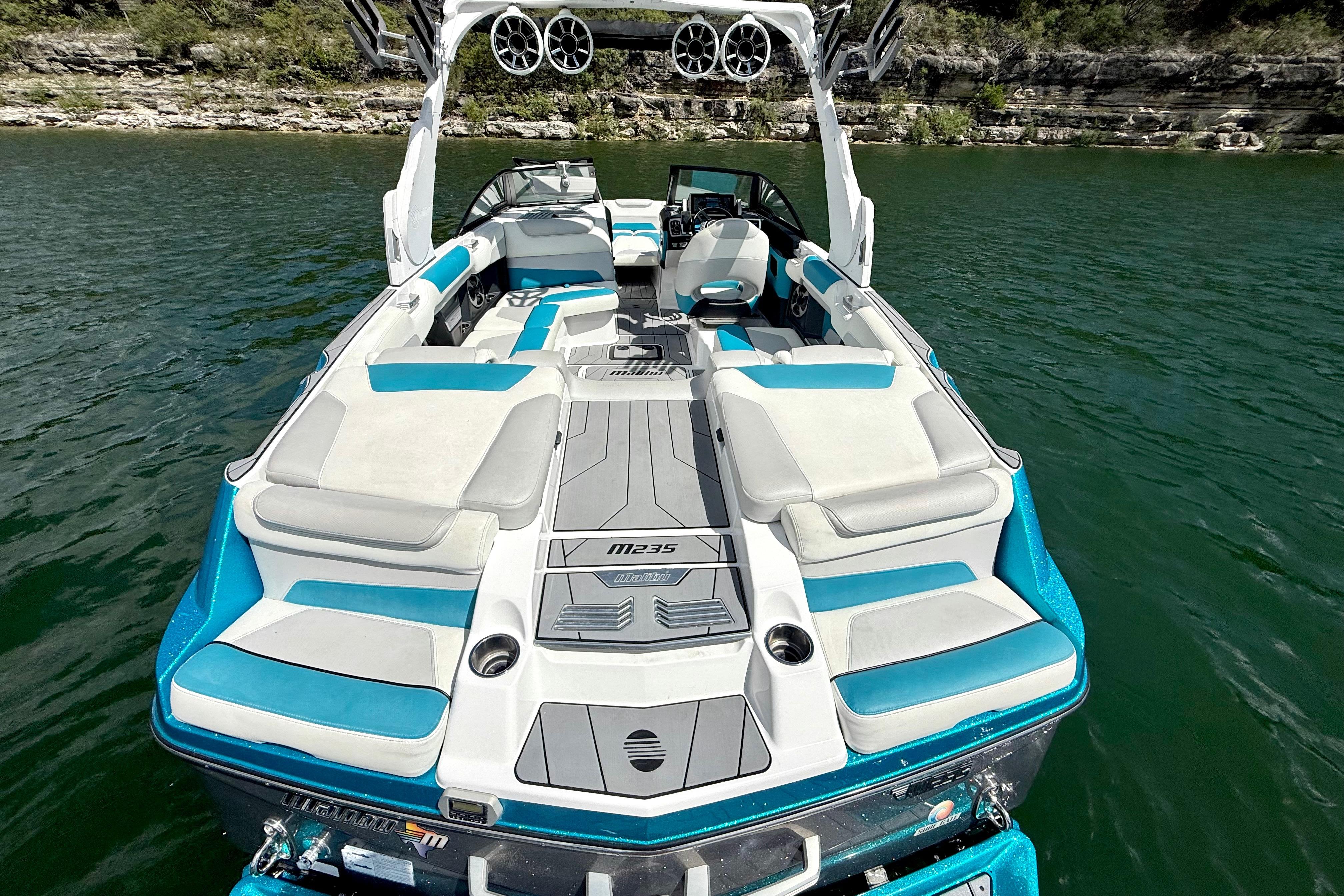 2017 Malibu M235 boat with blue and white seating on a lake.