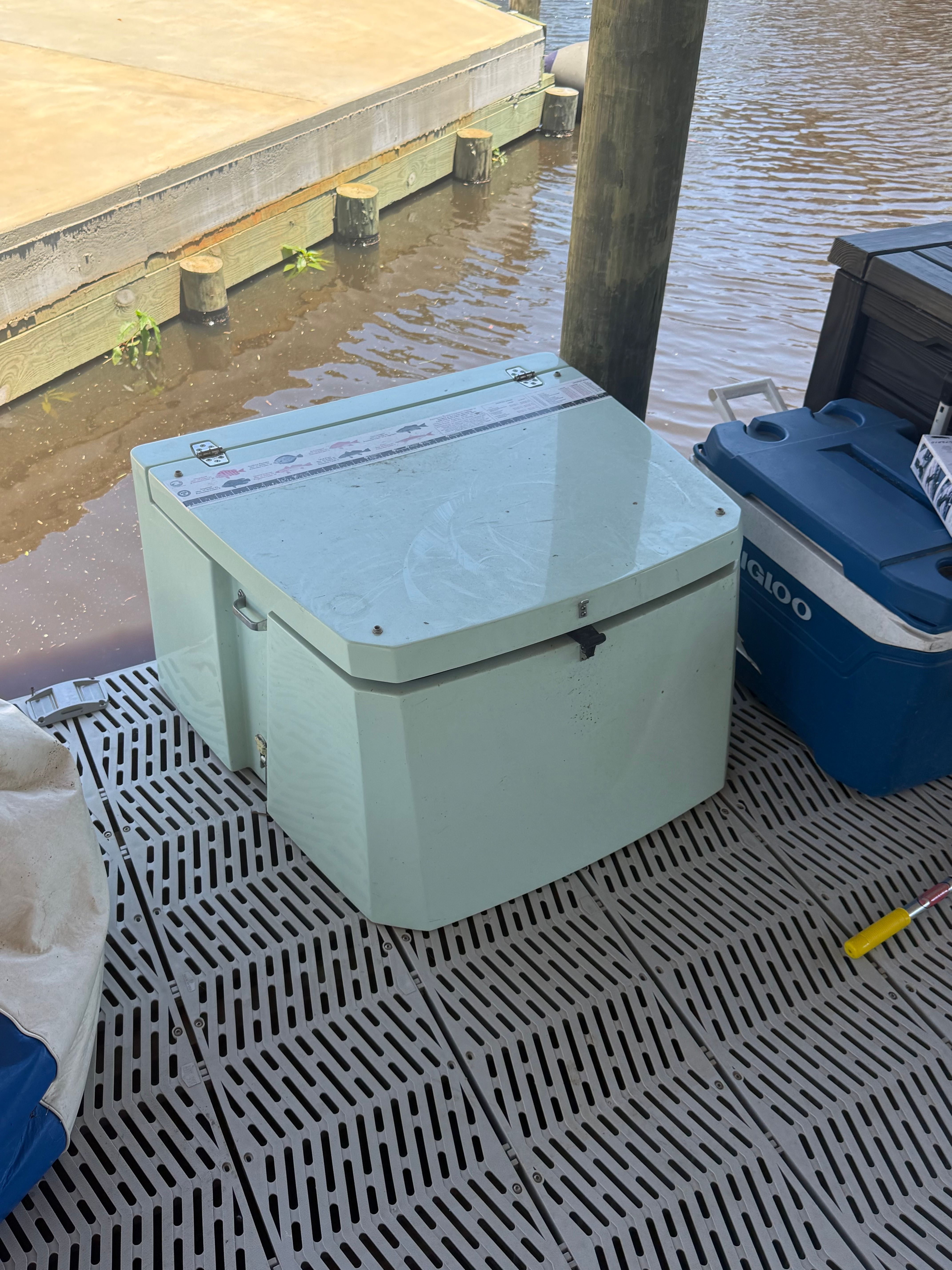 Coolers on a boat dock next to water.